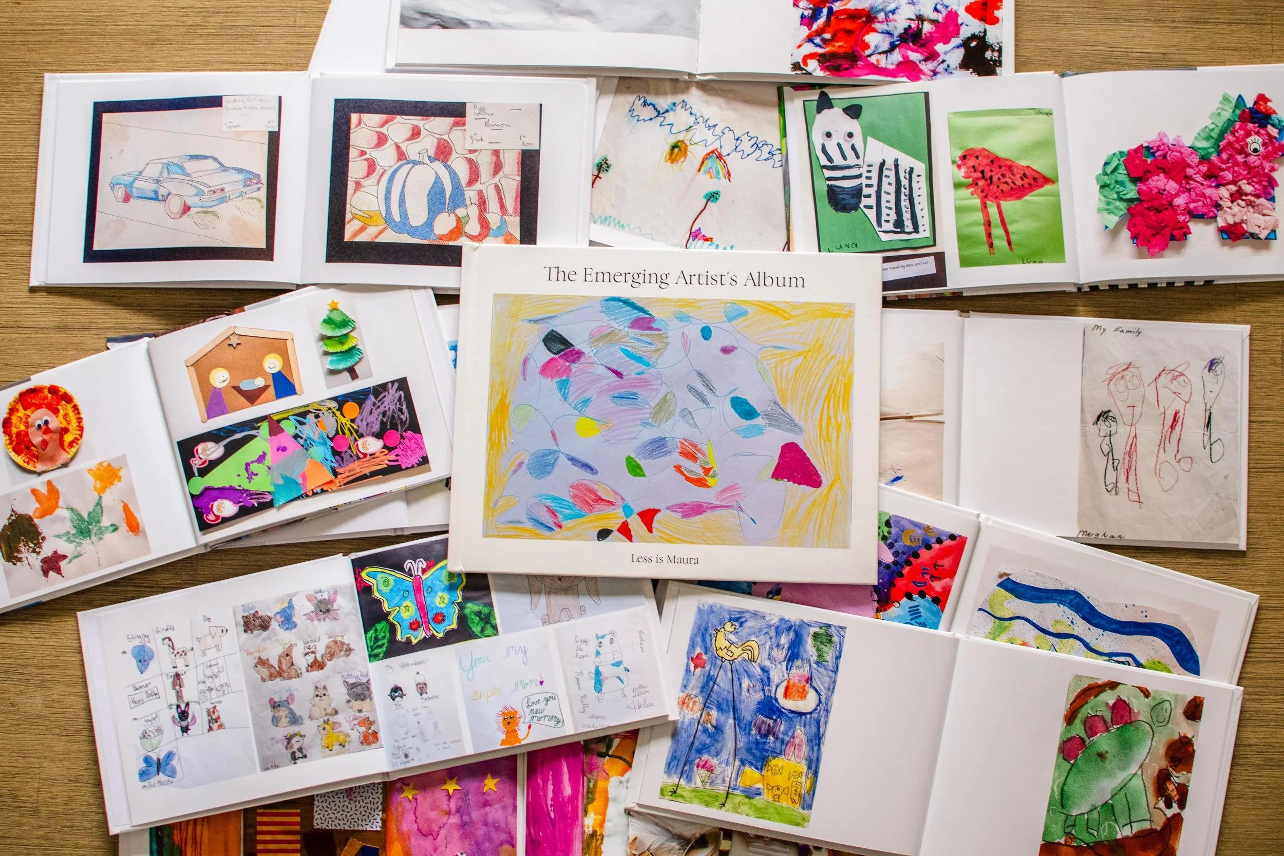 An Emerging Artist's Album lays on top of a dozen of individual albums opened to spreads of beautiful kid art.