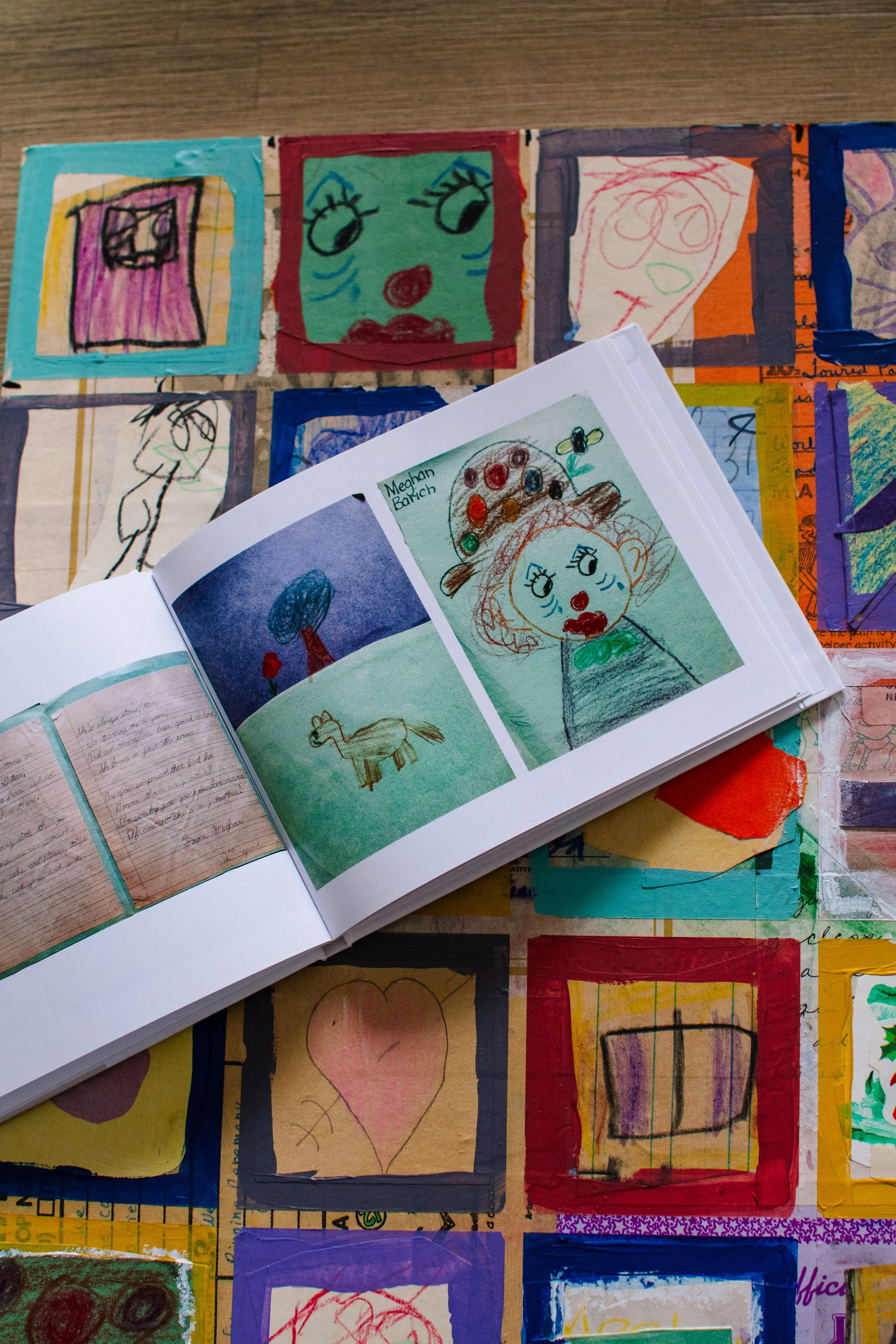 An art album lays open on top of a piece of mixed media art.