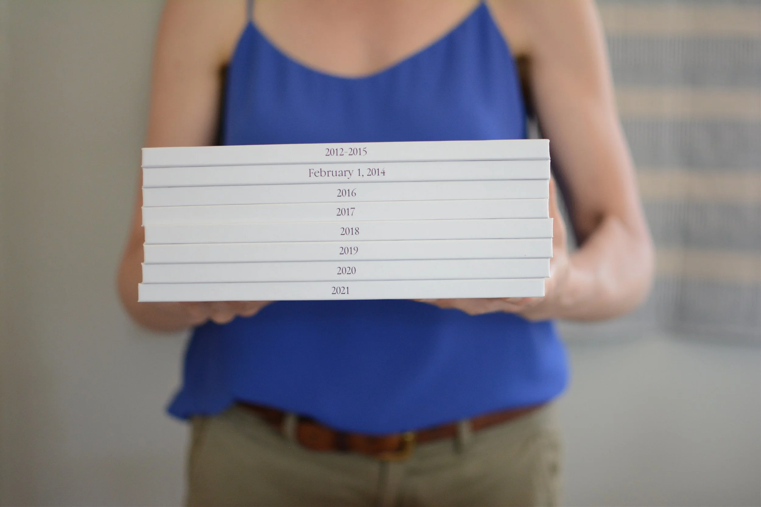 A woman holds a stack of albums.