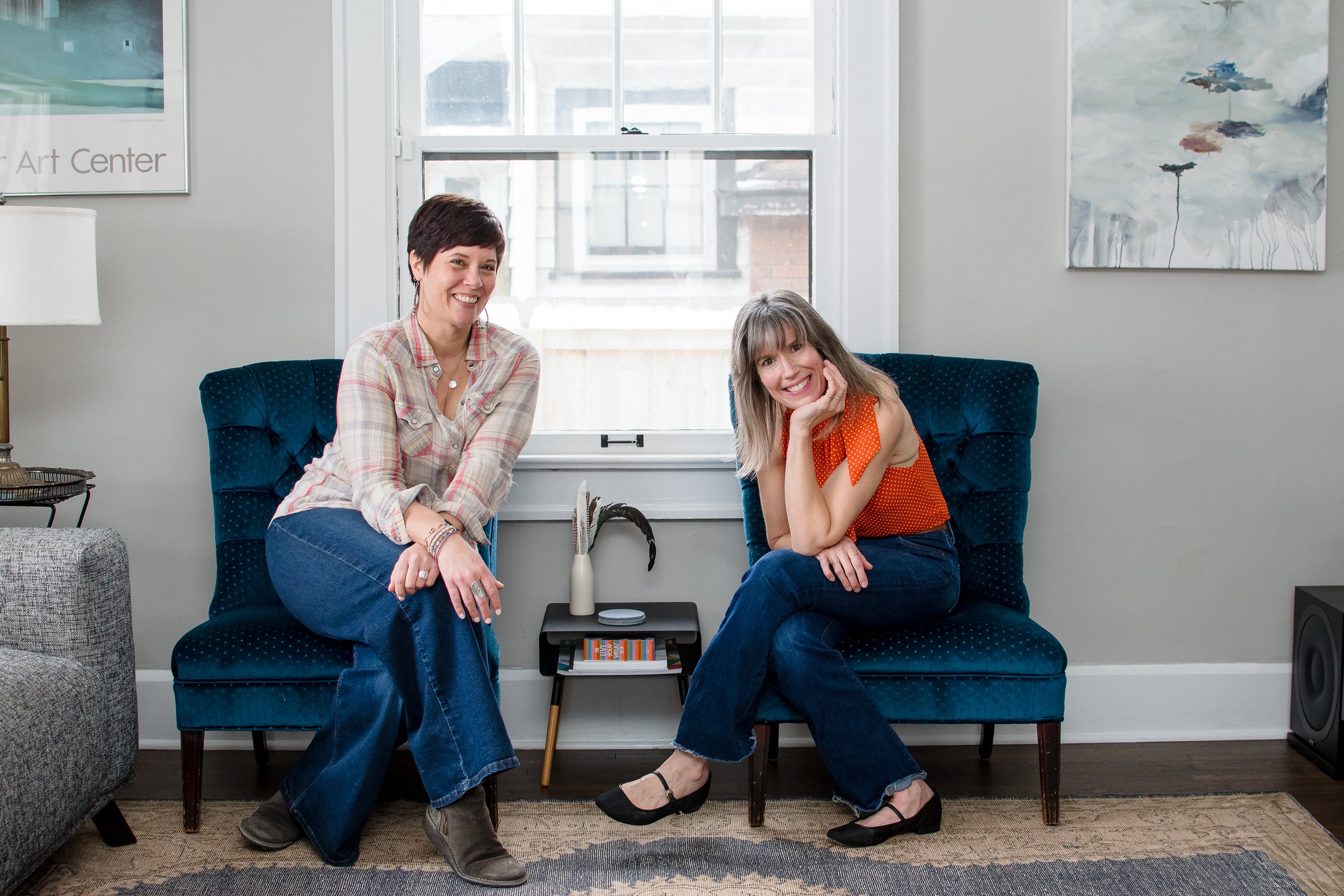 Meghan and Maura sit on blue chairs smiling at the camera