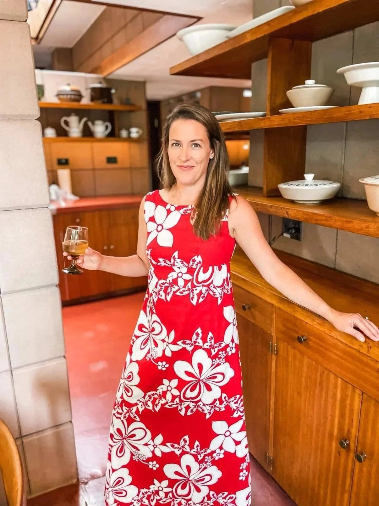 Awoman wears a red and white floral maxi dress.