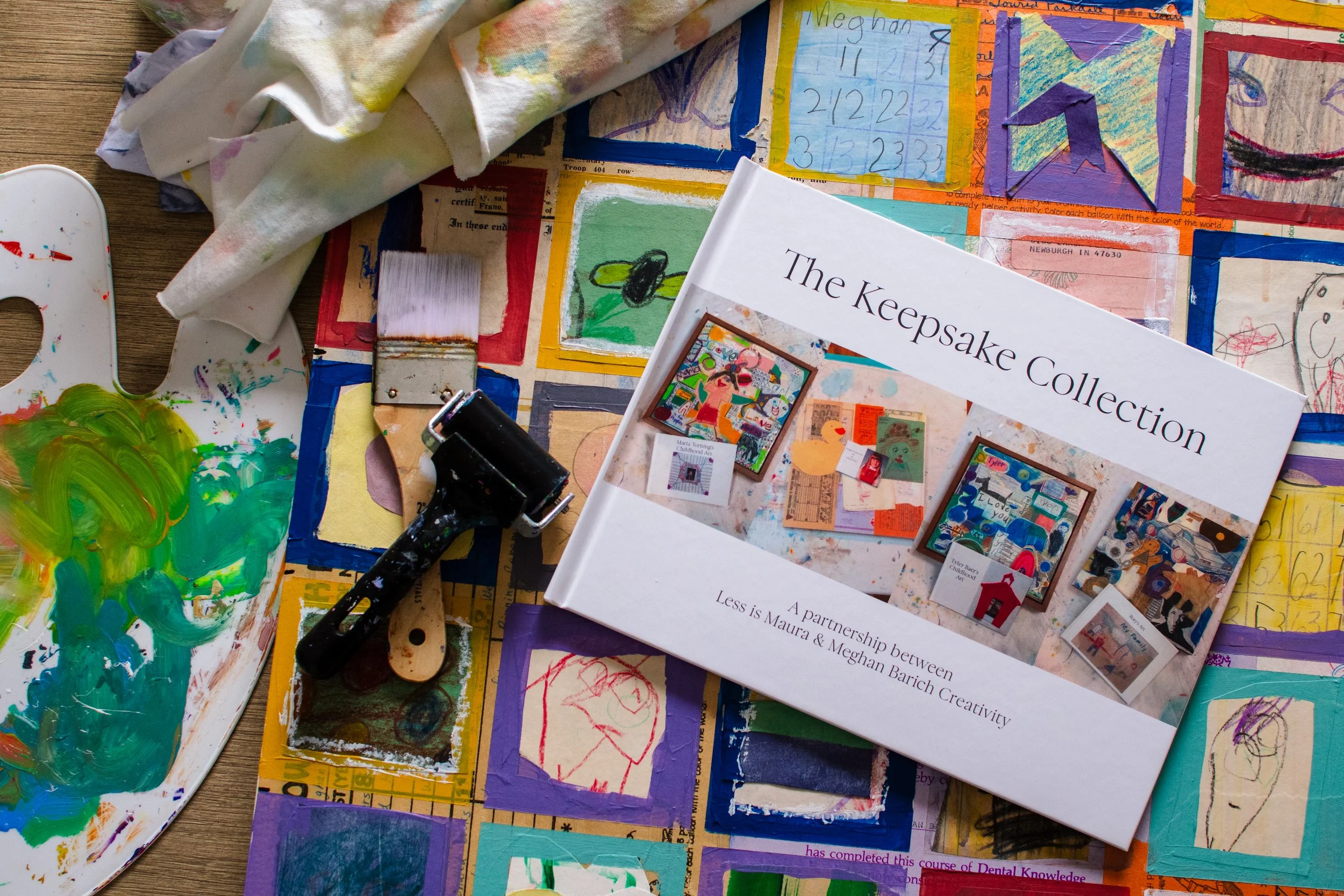 The Keepsake Collection album lays on top of a mixed media piece of art.