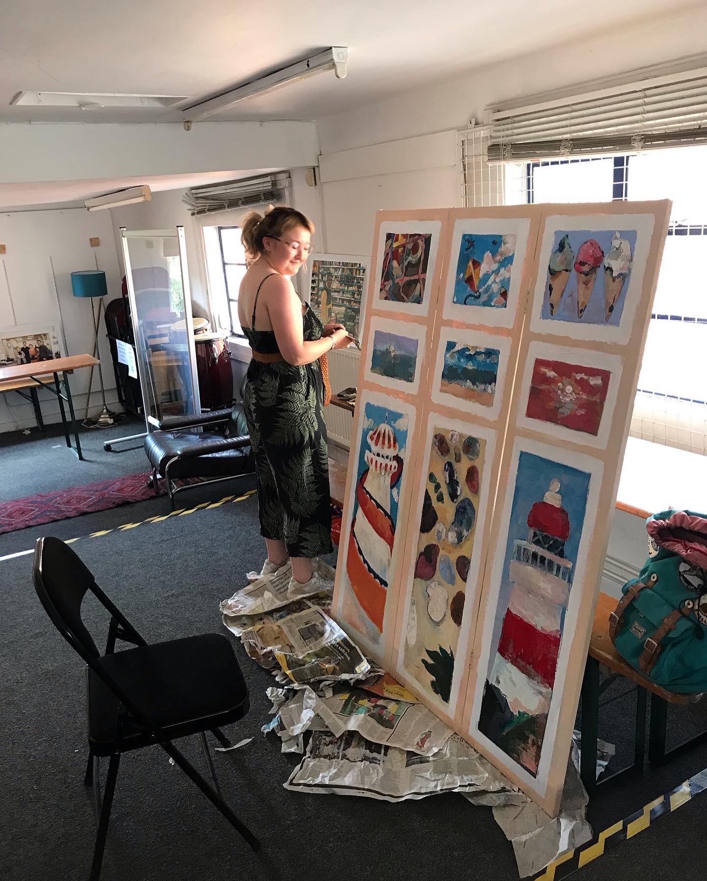 This is a picture of volunteer Jo, working on a large painting in the downstairs area of the Hive.