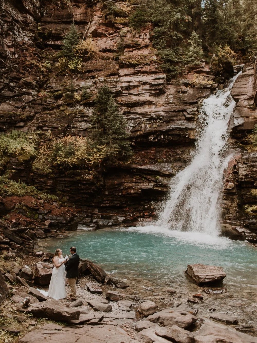 couple saying vows next to waterfall near silverton colorado