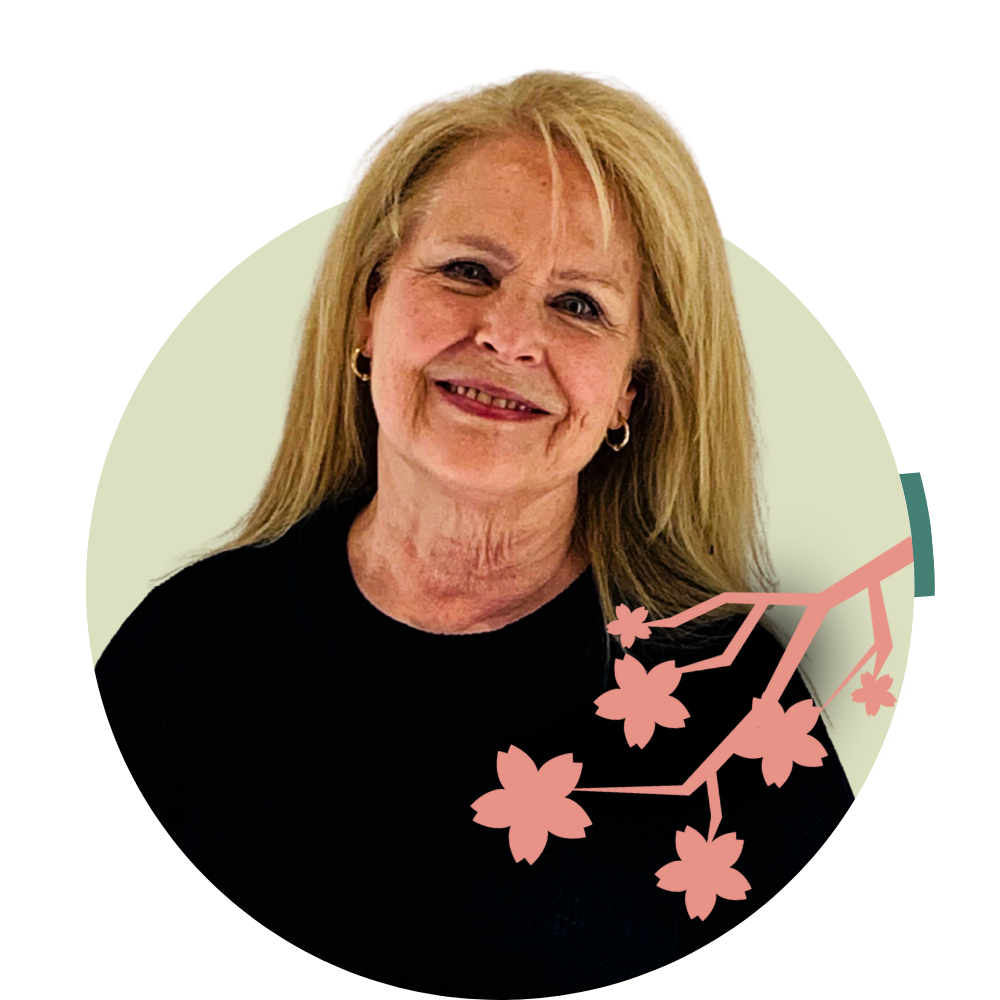 Thumbnail image of associate therapist Michelle Stockwell: An older woman with blonde hair smiling, wearing a black top and hoop earrings, with pink cherry blossom graphic overlay.