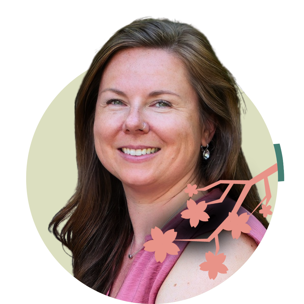 Thumbnail image of associate therapist Jennifer Hines: A woman with long brown hair, smiling, wearing a pink top, earrings, and a small nose piercing, with a background featuring a branch with pink flowers.