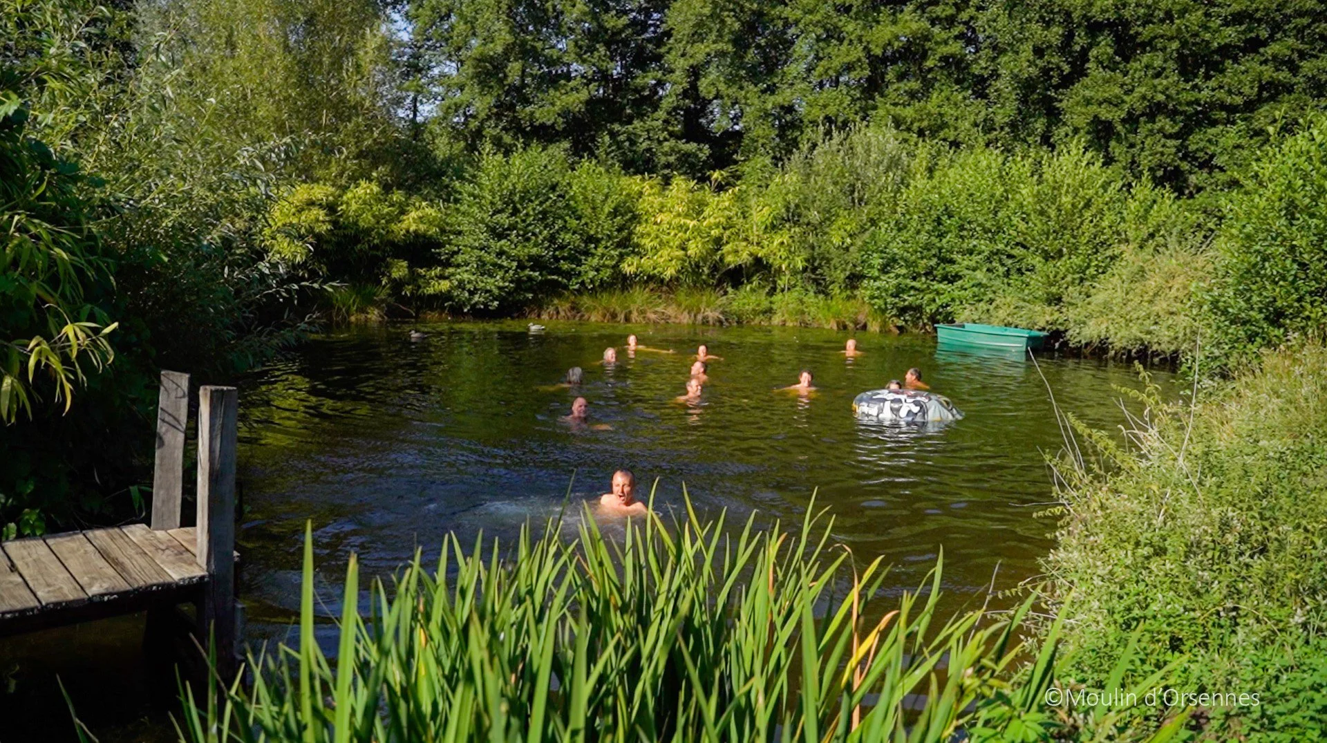 Deelnemers van Internal Therapie Systems retraite van Jeannine de Klerk zwemmen in een natuurlijke waterplas omgeven door groen struikgewas en bomen in het yoga centrum van Sadhaka in Frankrijk