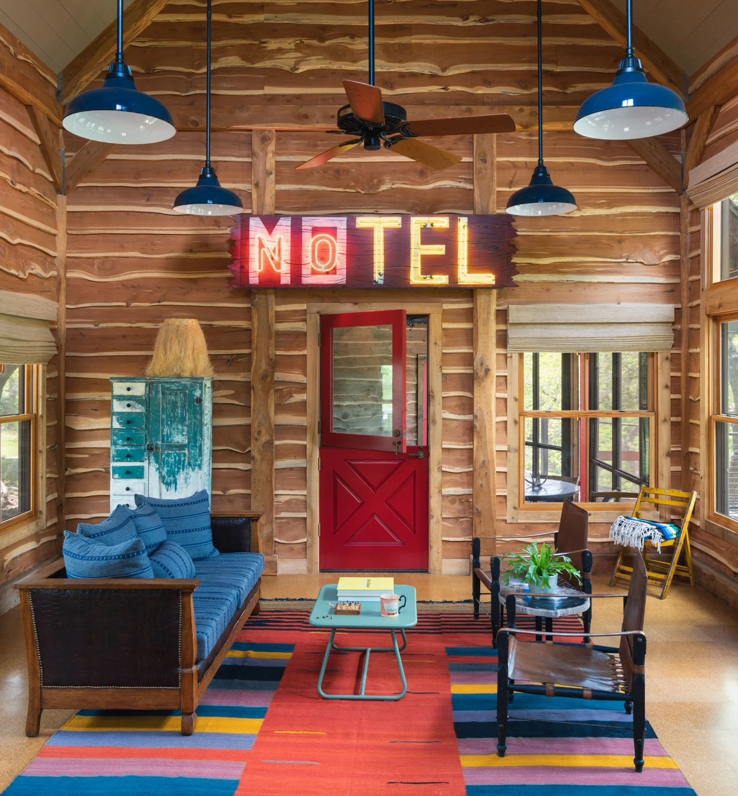 Colorful interior of Hill Country dog trot cabin with neon sign and cedar wall cladding