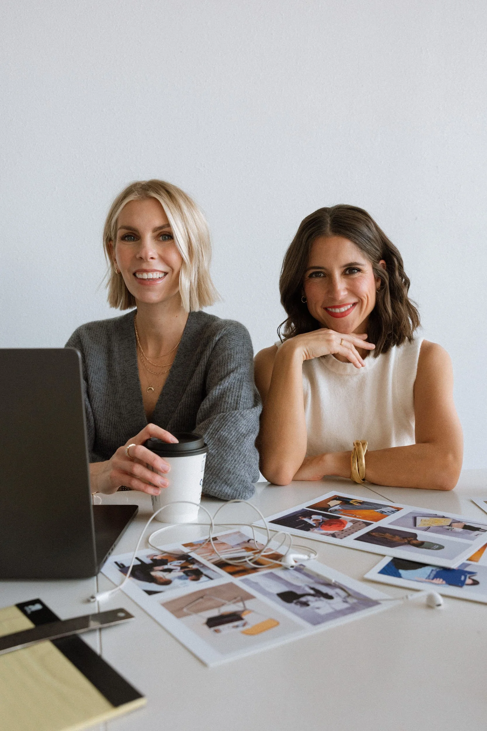 Website designer, Sara Beukema, and brand copywriter, Megan Hopkins, sitting at a desk reviewing print collateral and brand identity concepts.
