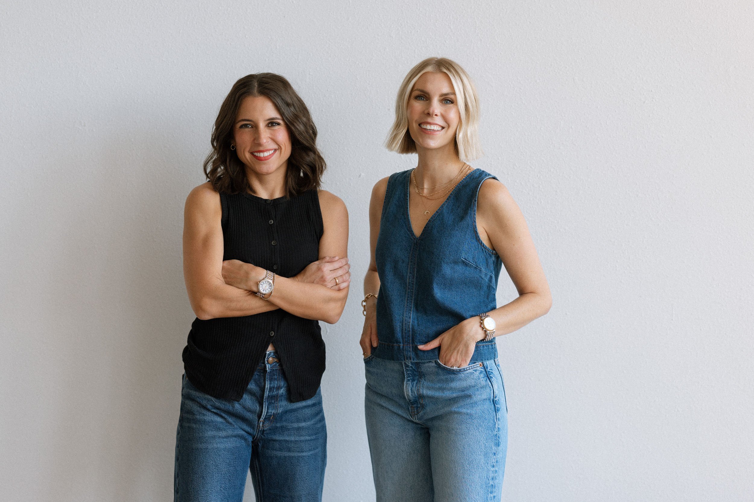 Megan Hopkins and Sara Beukema, co-founders of Merit & State branding agency, standing together against a white studio background.
