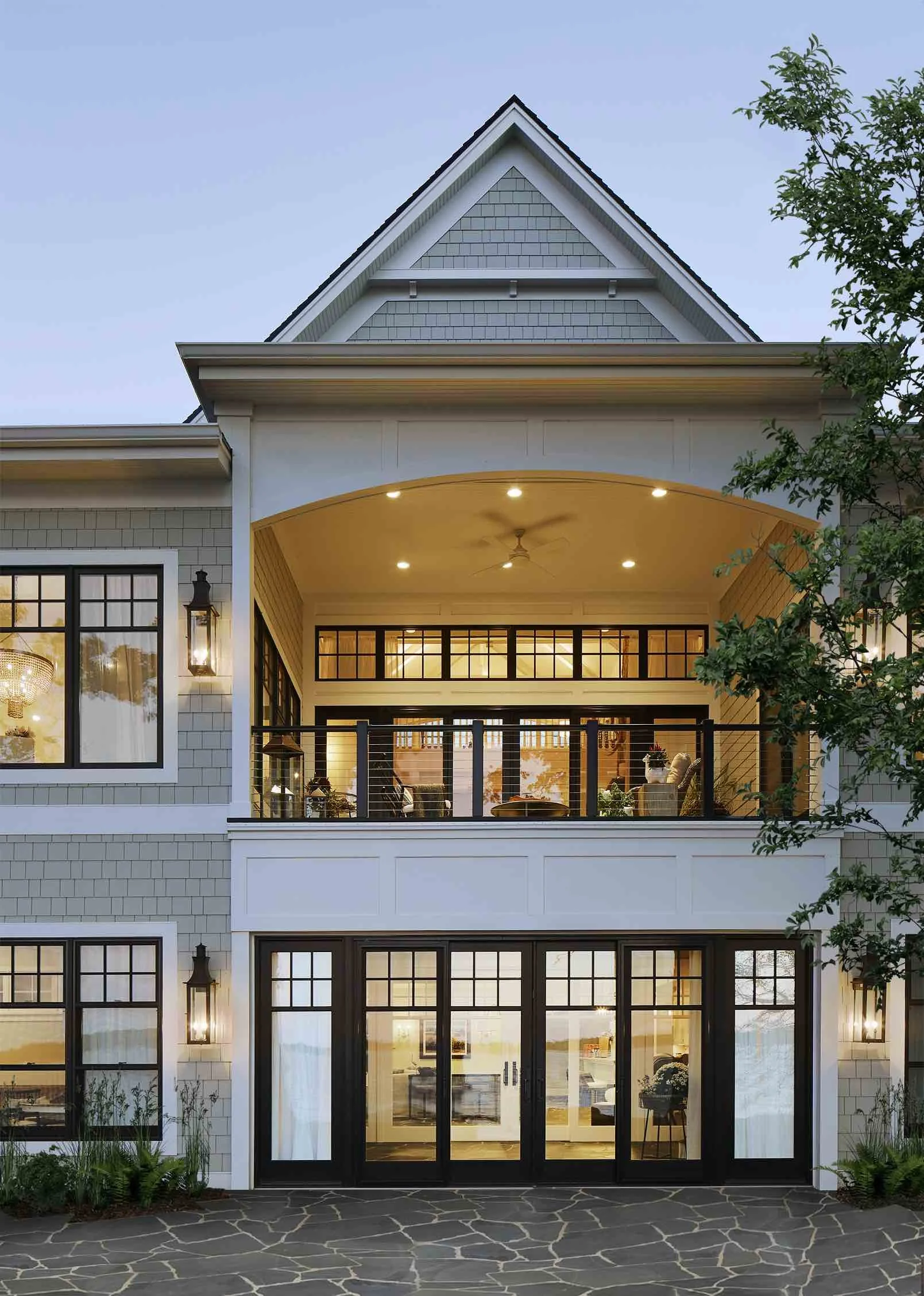 The outside of a lake house with tan and white siding and black trim