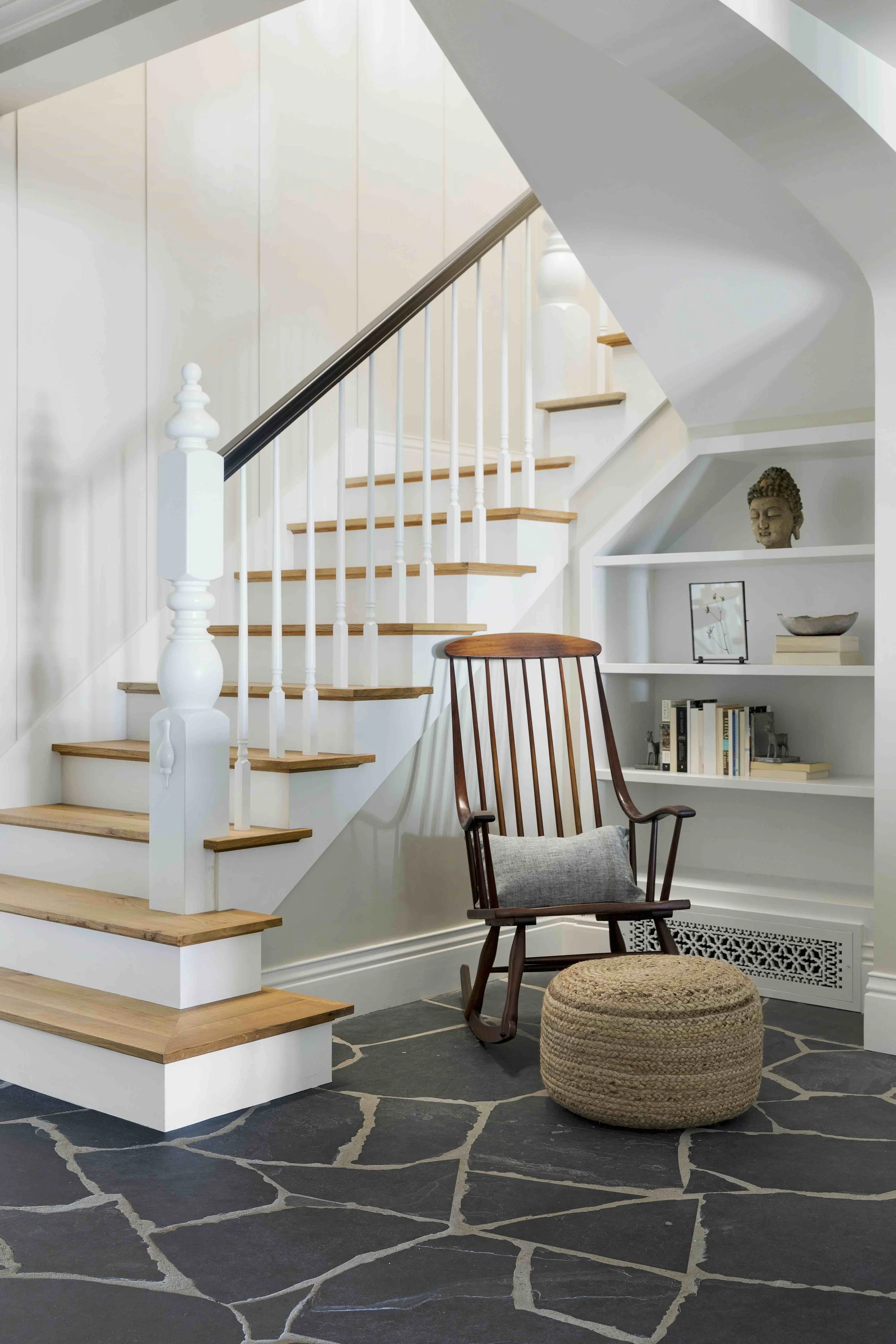 A white and natural wood staircase with built-in shelves and reading nook