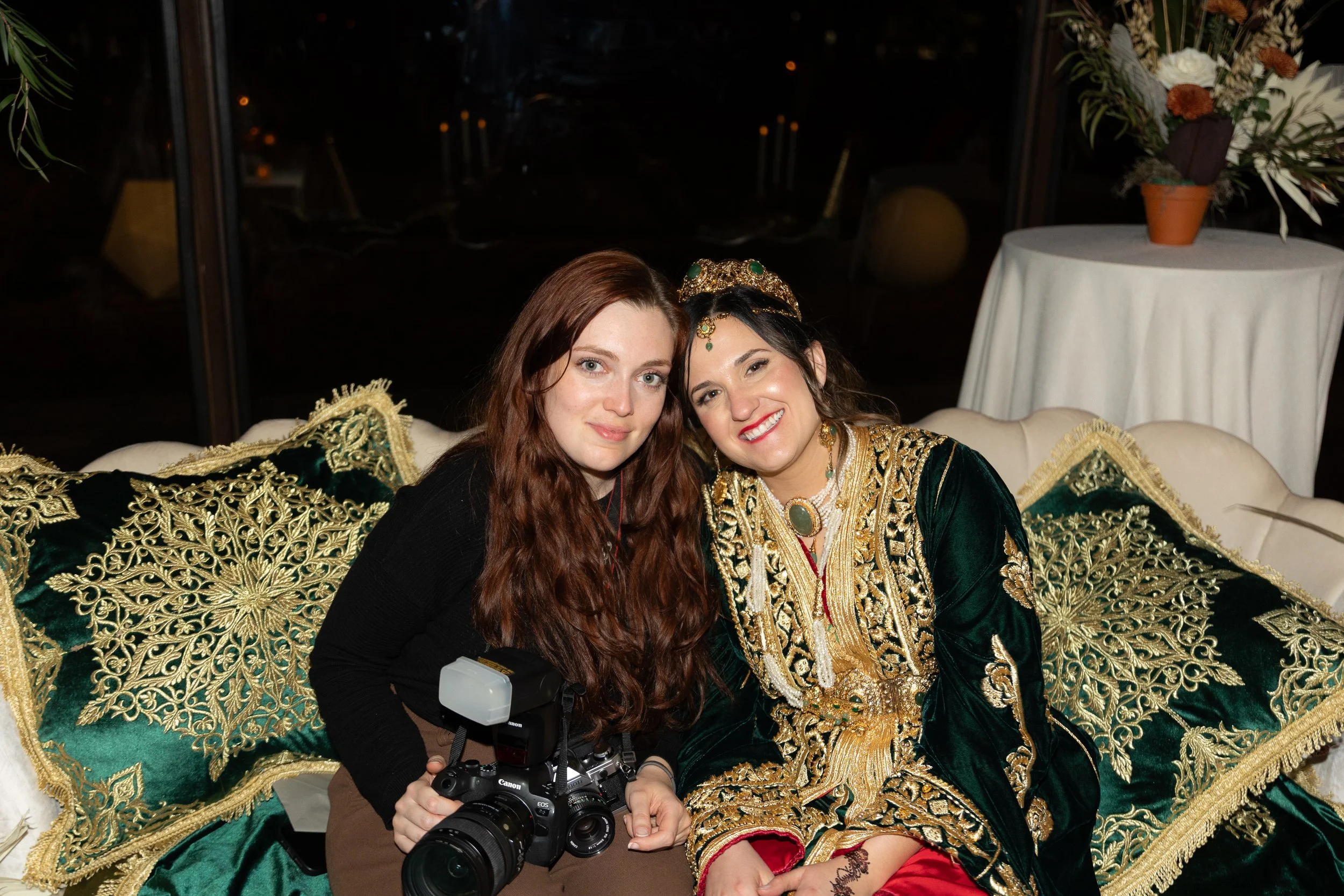 Sam is sitting with a bride at her wedding reception. Both are smiling at the camera