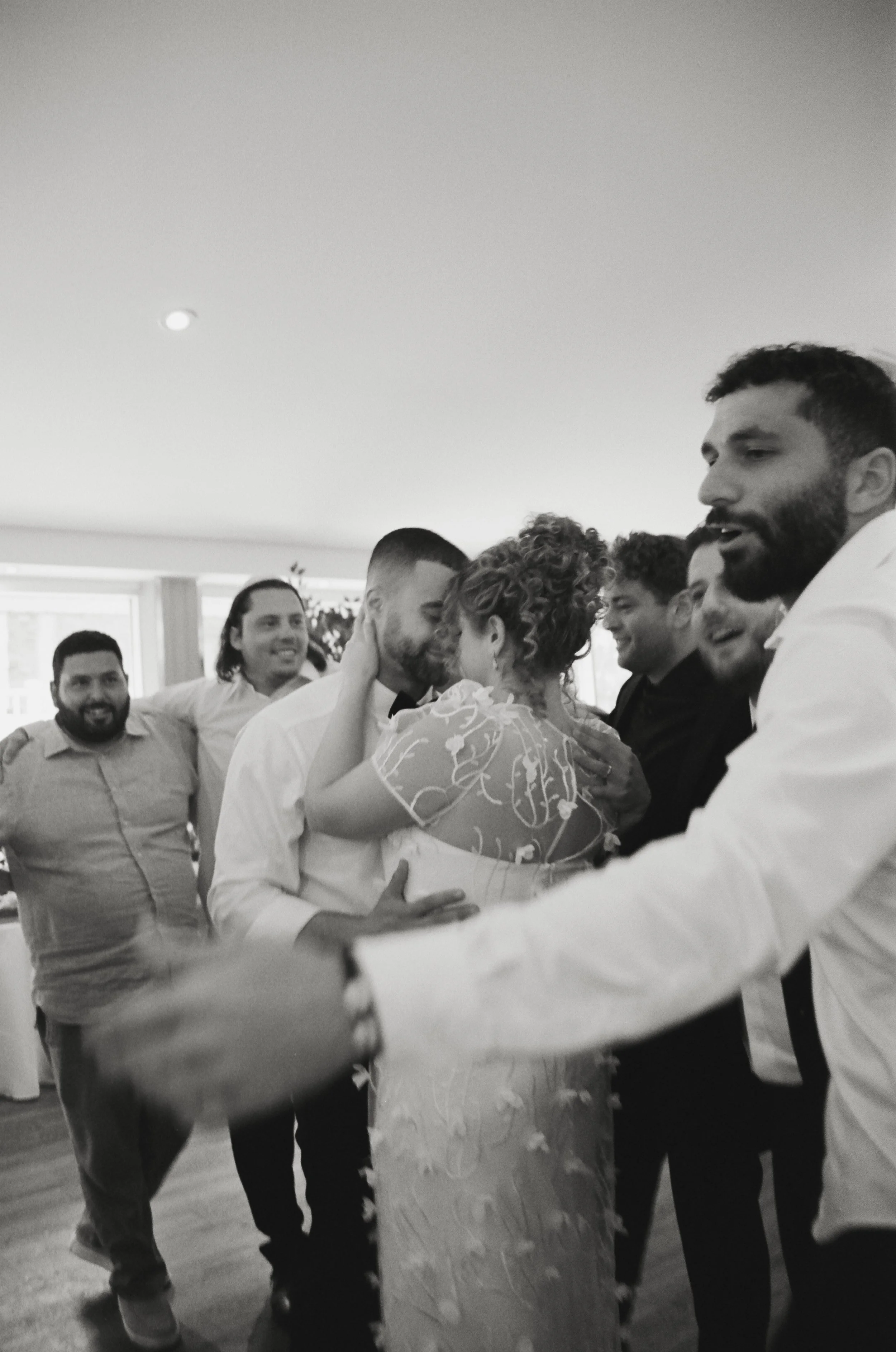 a newlywed couple slow dances together, with guests standing around them in a circle.