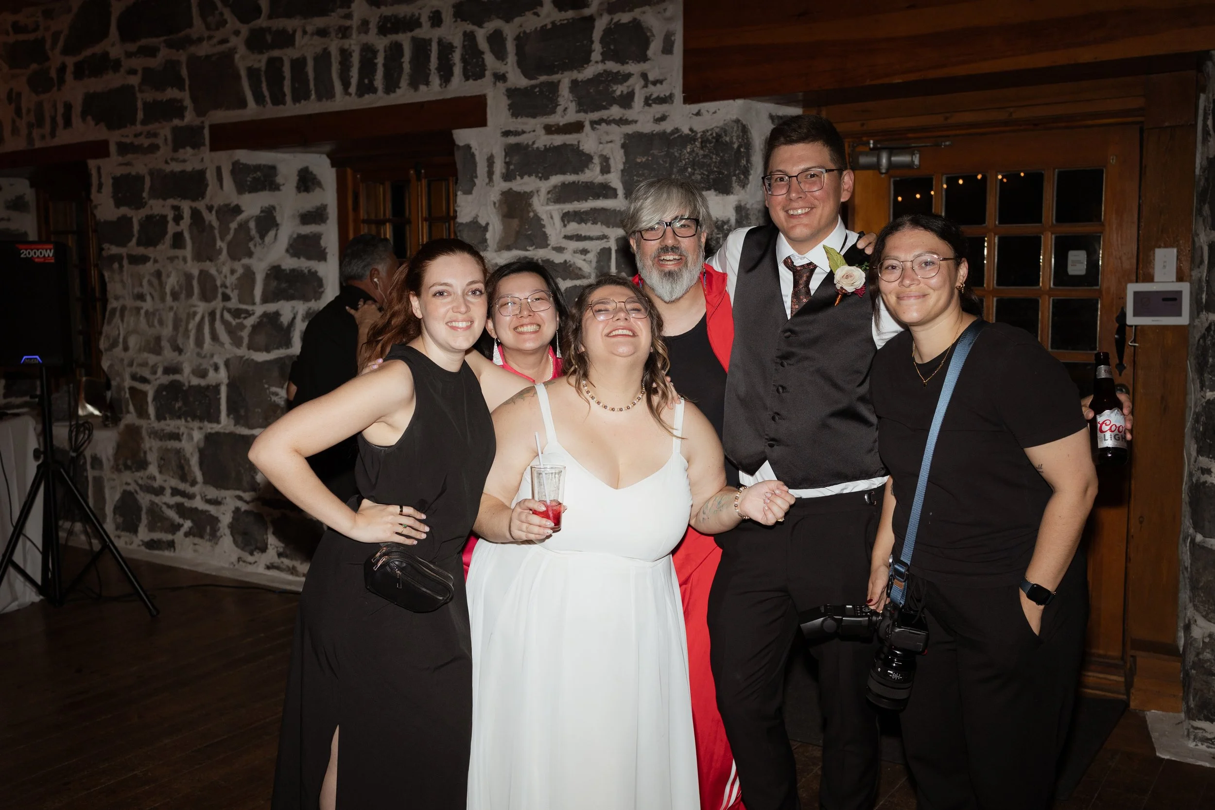 Sam, her assistant photographer and the DJ stand with the bride and room as the reception. Everyone is smiling and laughing together.