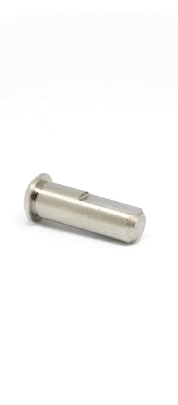 A metallic cylindrical tool or part with a rounded flange on one end, lying on a white surface.