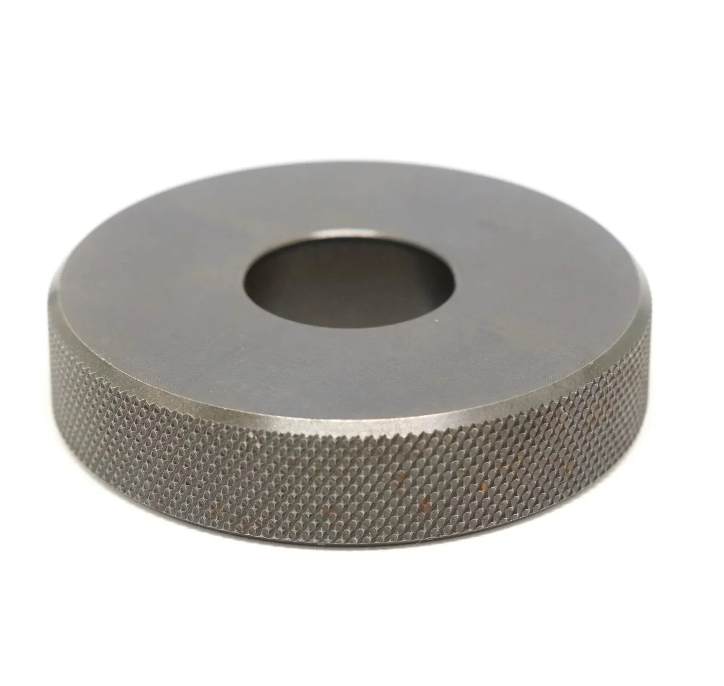 A round metallic object with a textured outer edge and a central hole. 