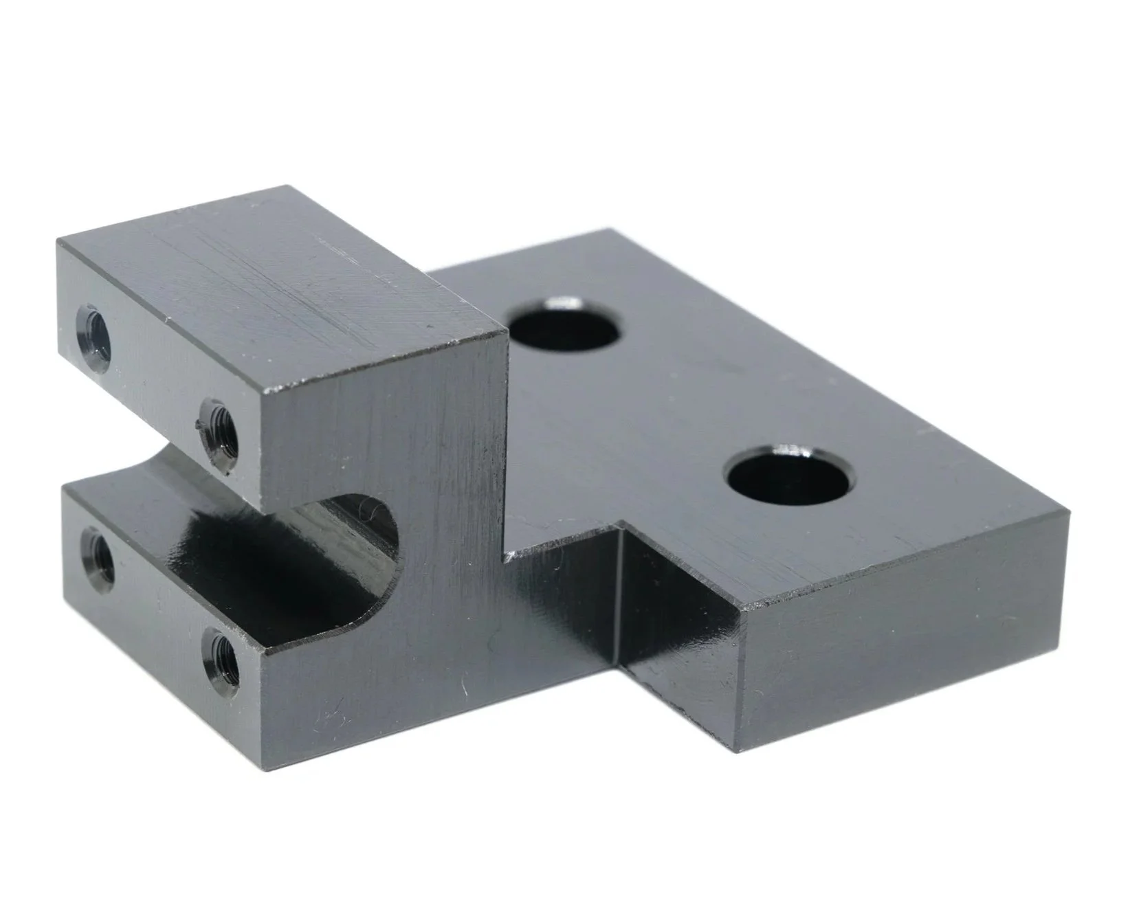 Metal machine part with multiple threaded holes and a slot, shiny and reflective surface.