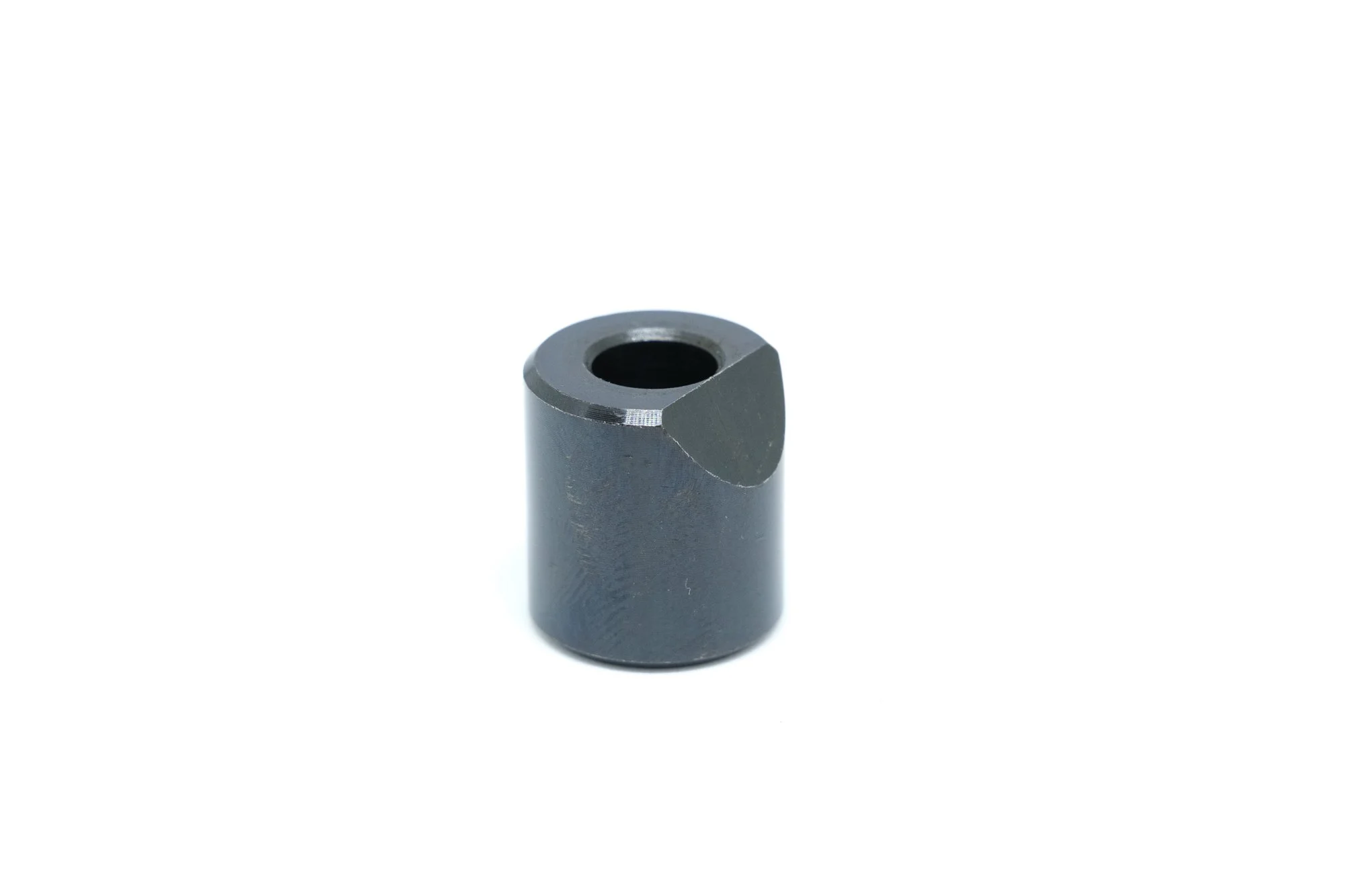 A small, cylindrical, black metal part with a cutout on one side and a central hole, isolated on a white background.