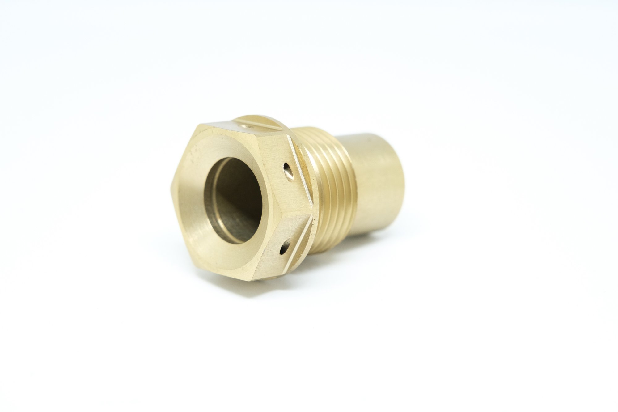 A metallic brass fitting with a hexagonal shape, threaded exterior, and a hollow interior, isolated on a white background.