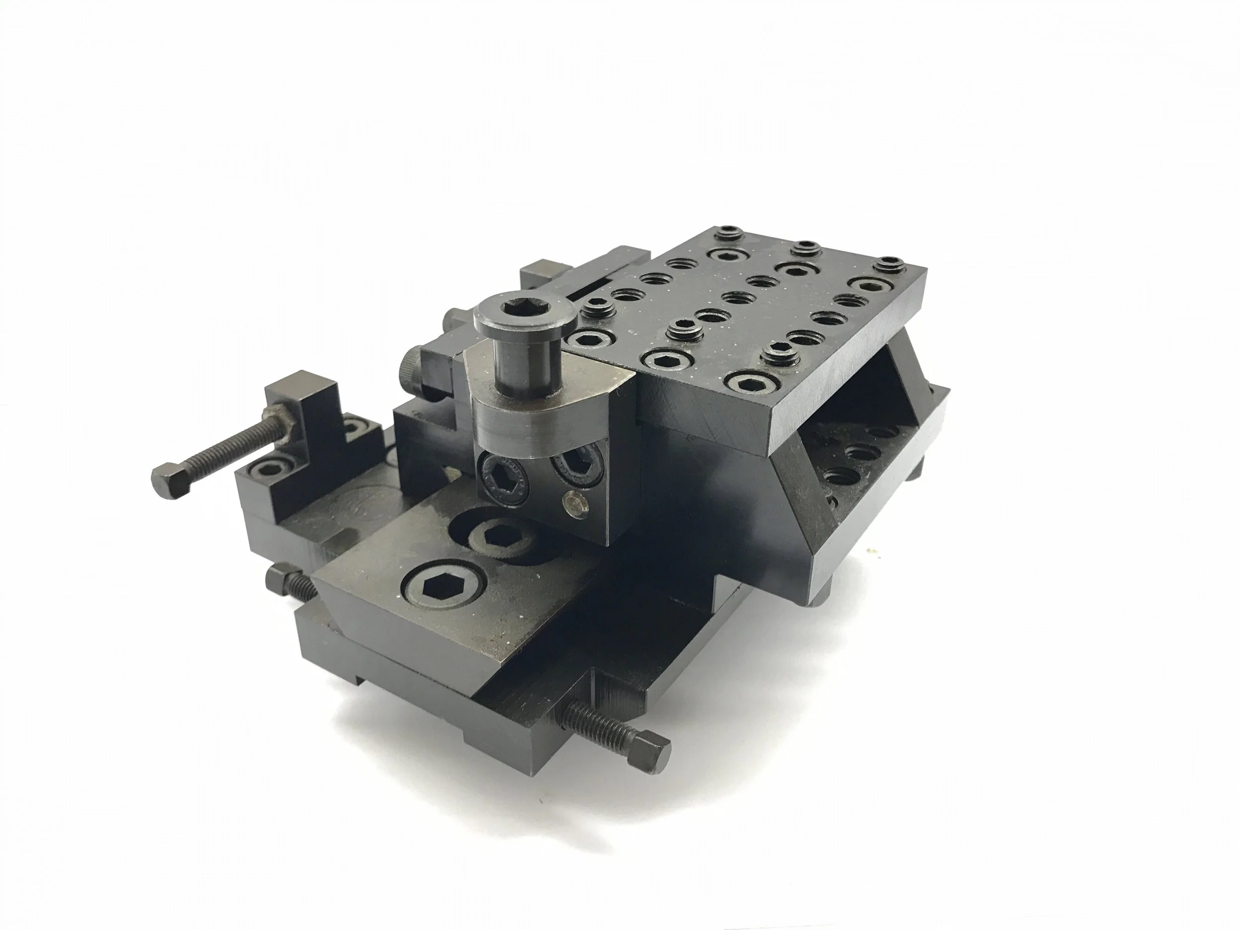 A metal machine part with various screws, bolts, and adjustable components, likely used in manufacturing or technical assembly.