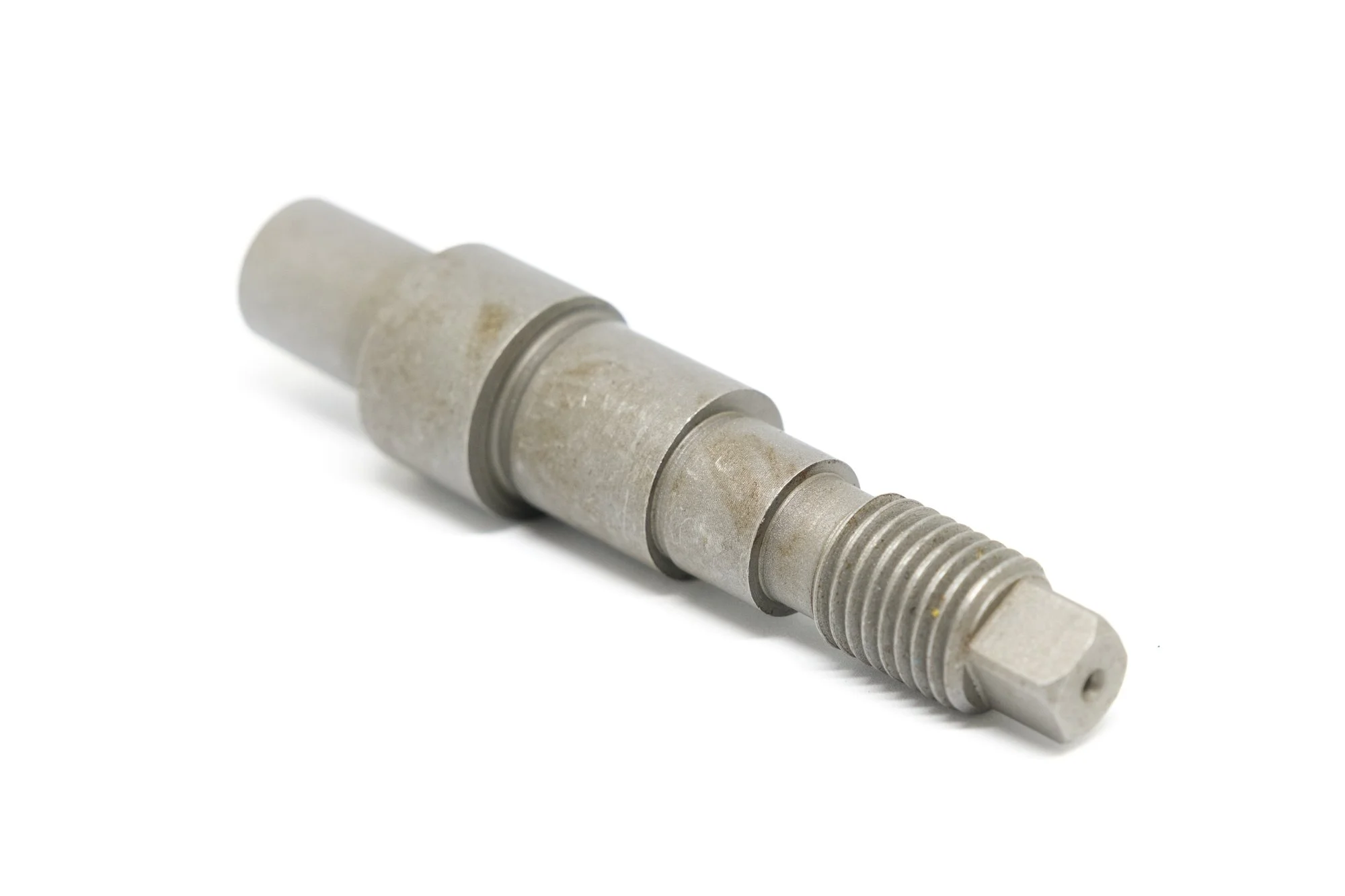 Close-up of a metal engine part with threaded and smooth sections on a white background.