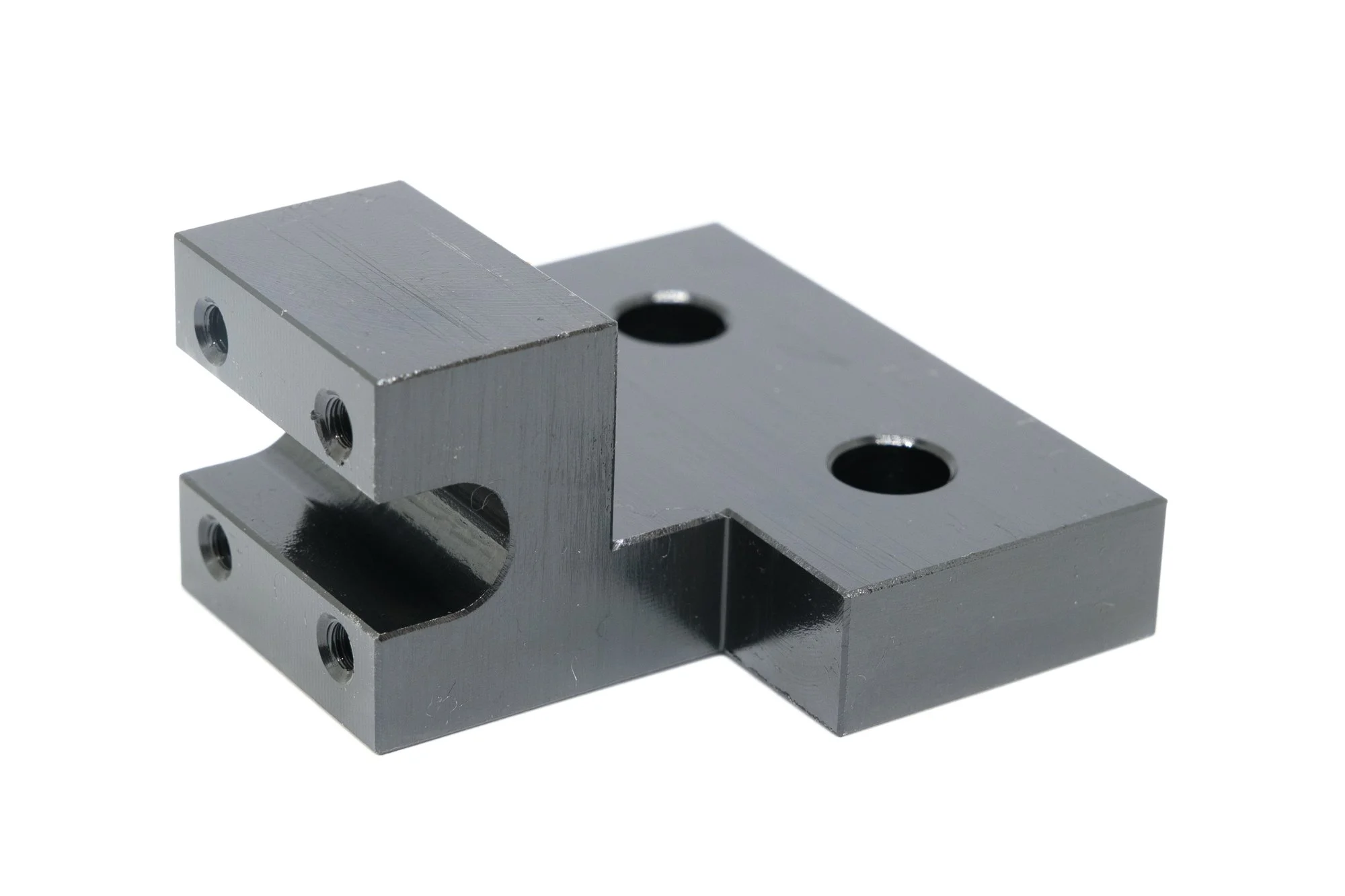 Metal machine part with multiple holes and a U-shaped cutout, finished with a smooth, dark surface.