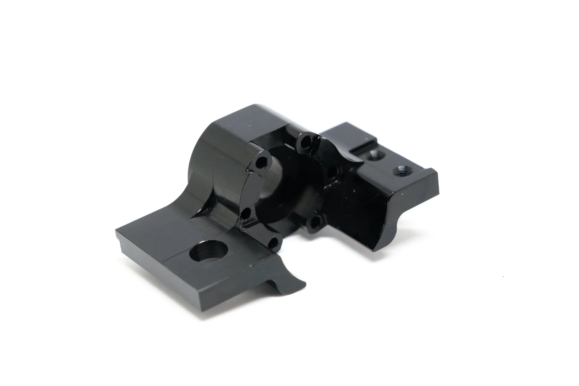 Black metal mechanical part with multiple holes and mounting points on a white background.