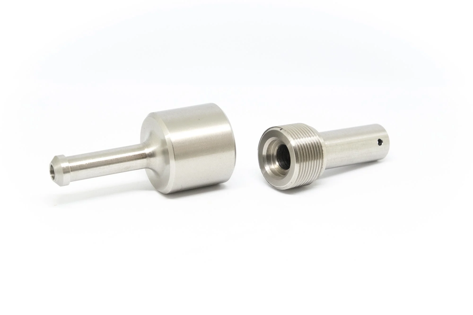 Two metallic cylindrical mechanical parts on a white surface