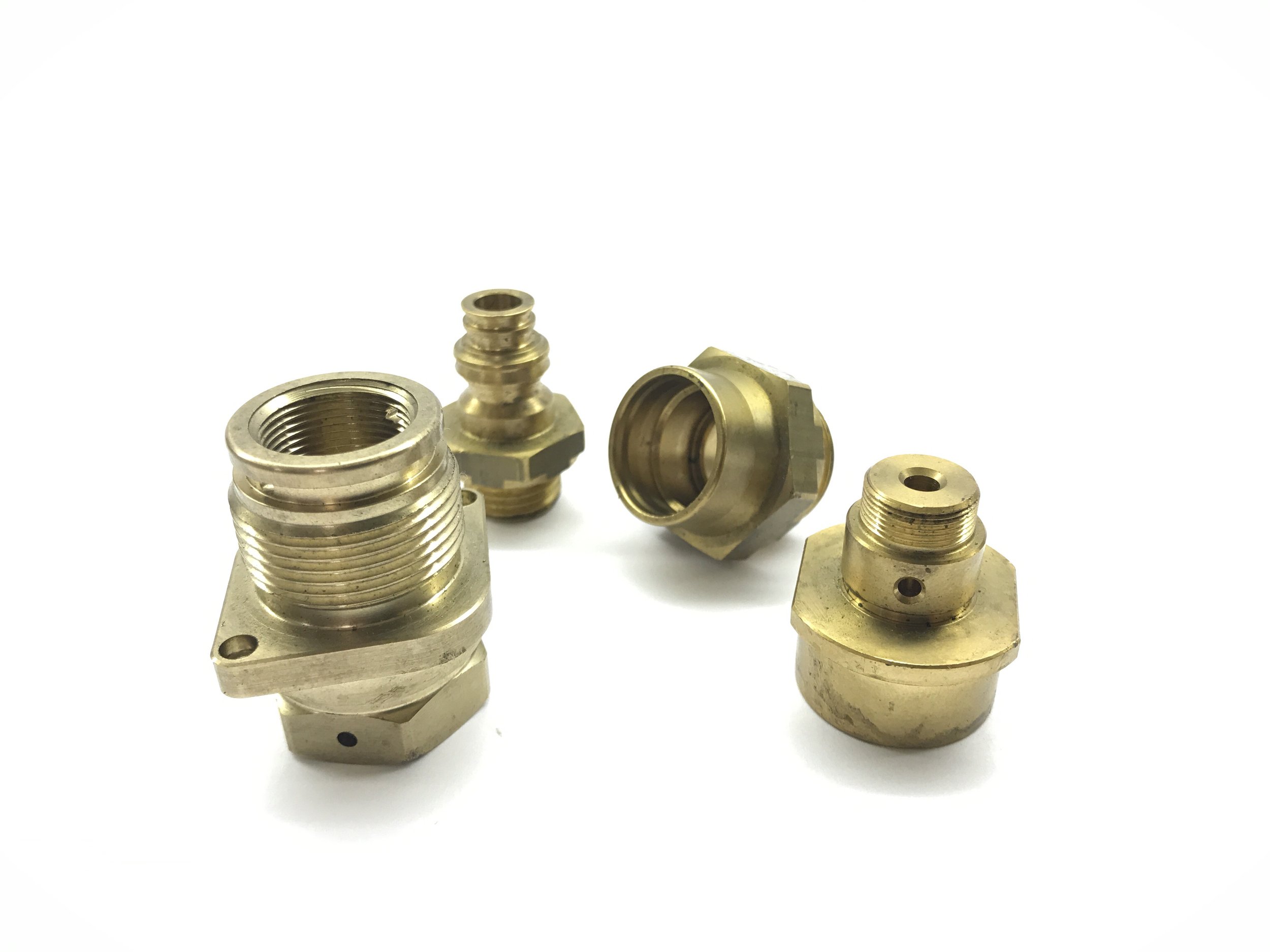 Five brass fittings with threaded ends and hexagonal bases on a white background.