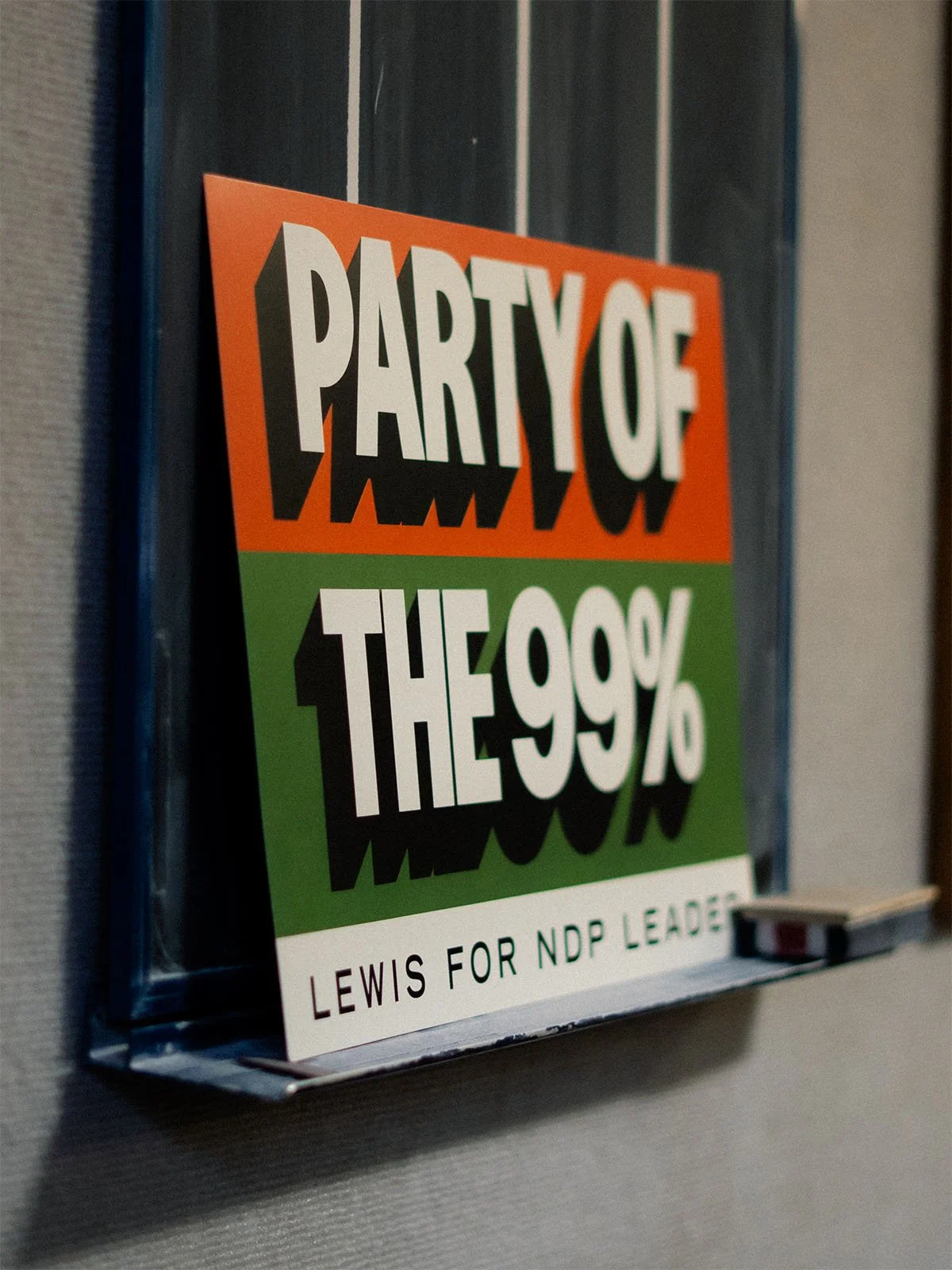 A branded sign resting on a darts scoreboard in a Royal Canadian Legion reads 'Party of the 99%'