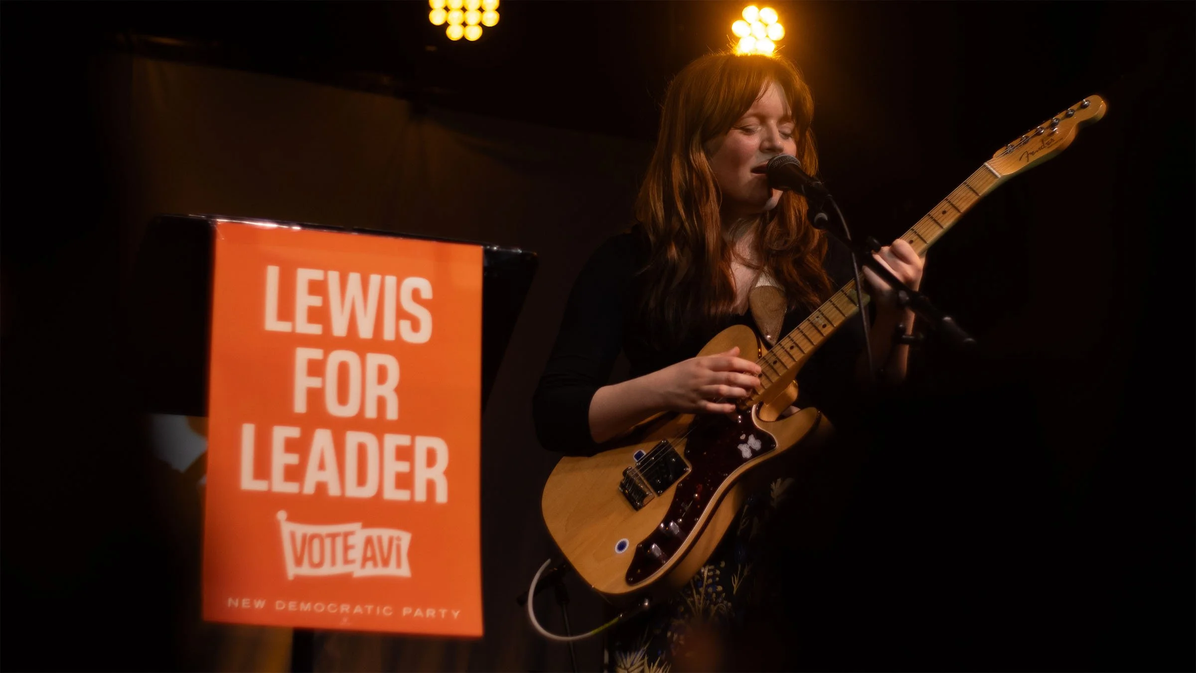 Toronto-based indei musical artist Housewife plays her telecaster and sings with a Lewis for Leader sign to the left