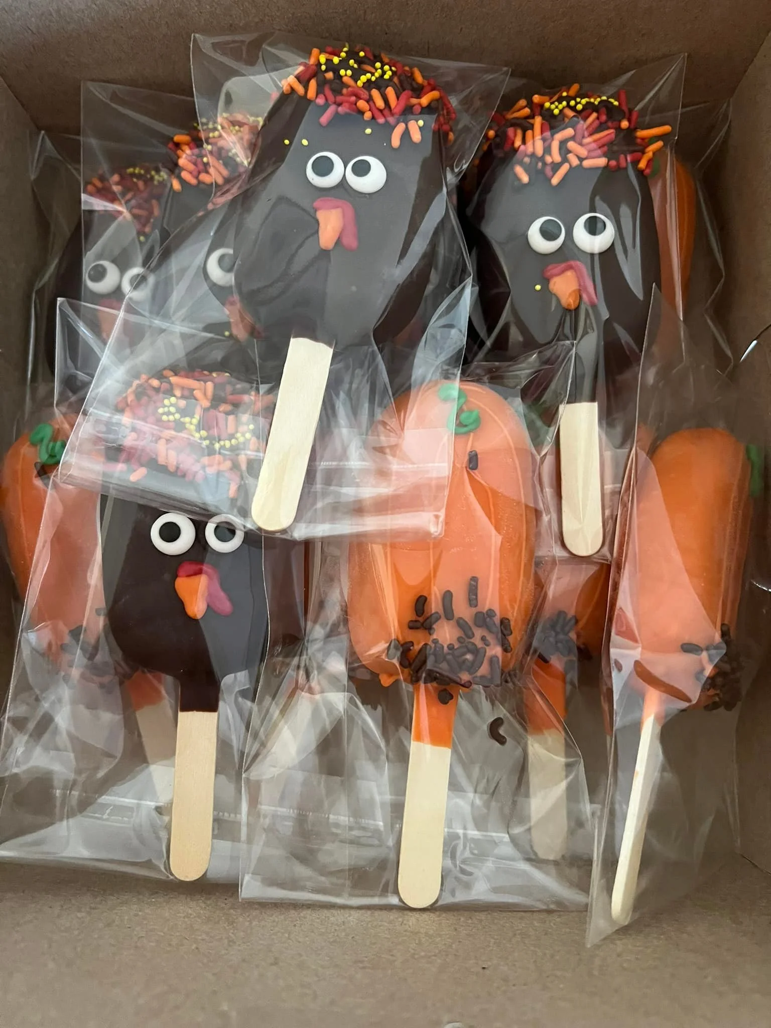 Halloween-themed Cakesicles decorated with gooey faces, sprinkles, and orange frosting