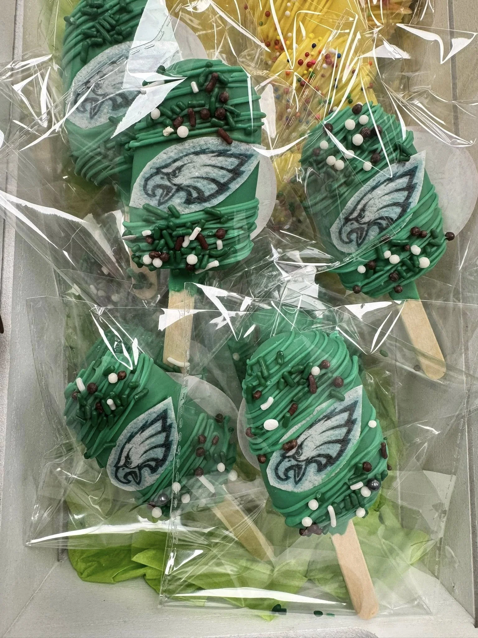Philadelphia Eagles themed Cakesicles with green icing, sprinkles, and an Eagles logos