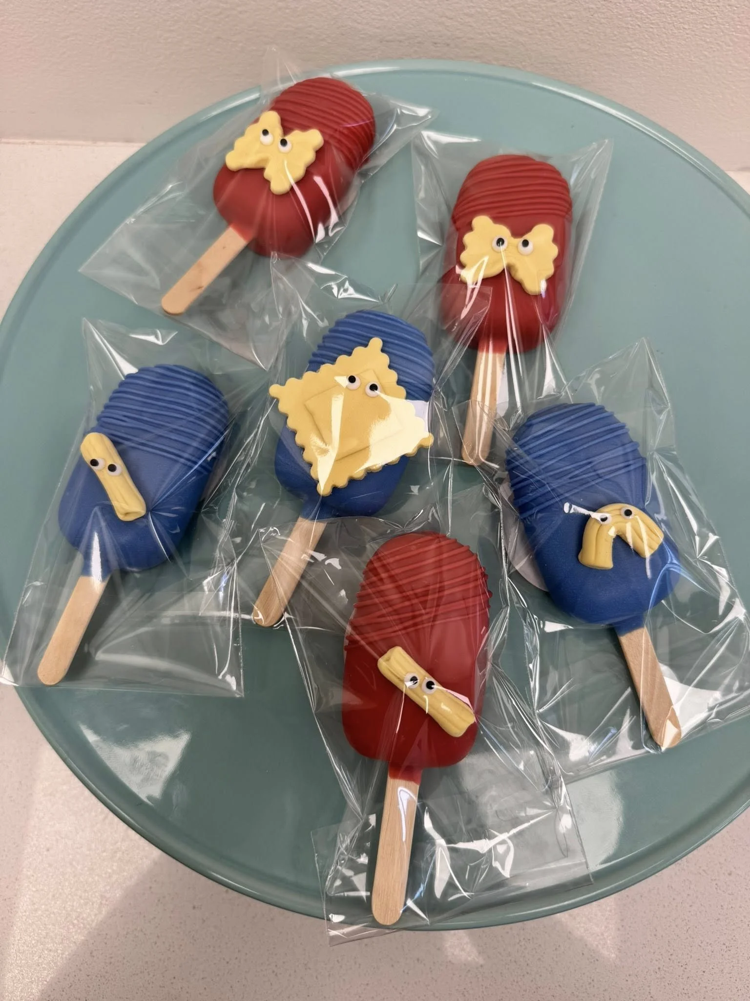 Colorful Cakesicles decorated with small yellow fondant accents 