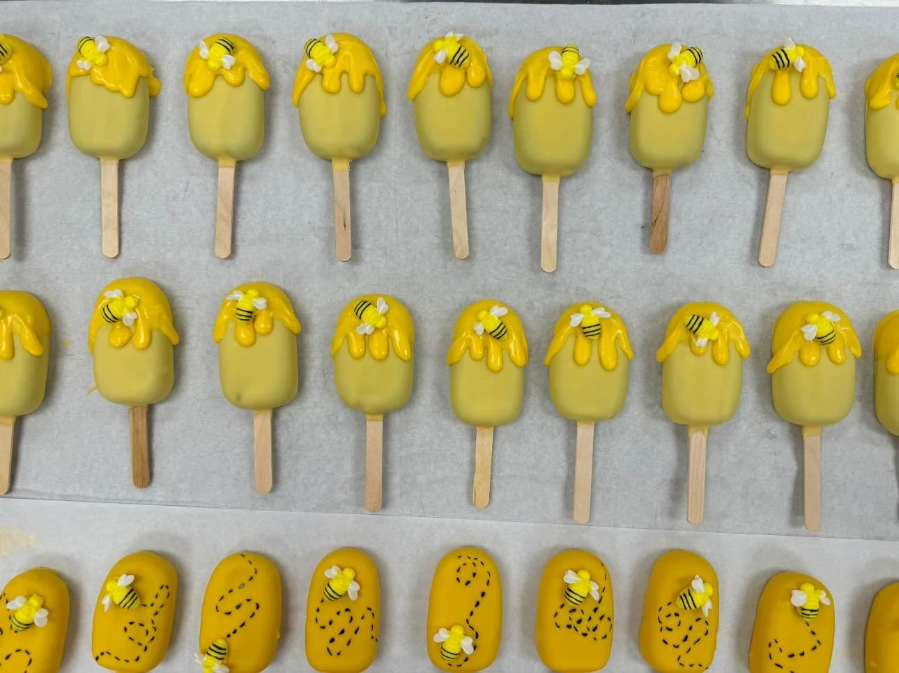 Yellow Cakesicles decorated with small bee and flower ornaments