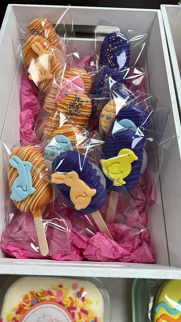 Colorful Easter-themed Cakesicles decorated with bunny and chick shapes, some with rainbow sprinkles
