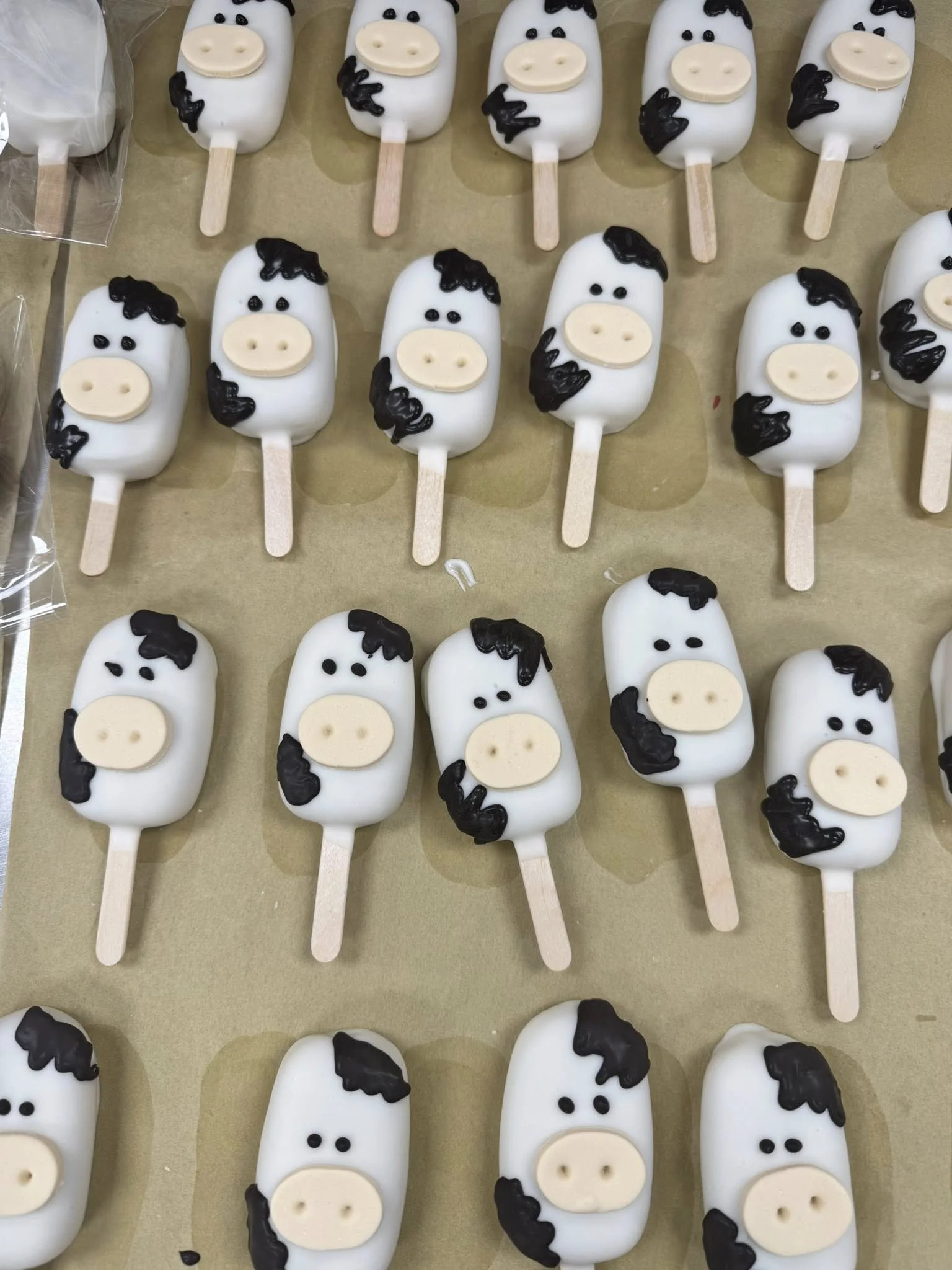 Cakesicles decorated as pigs faces with white chocolate, black hair, and black eyes.