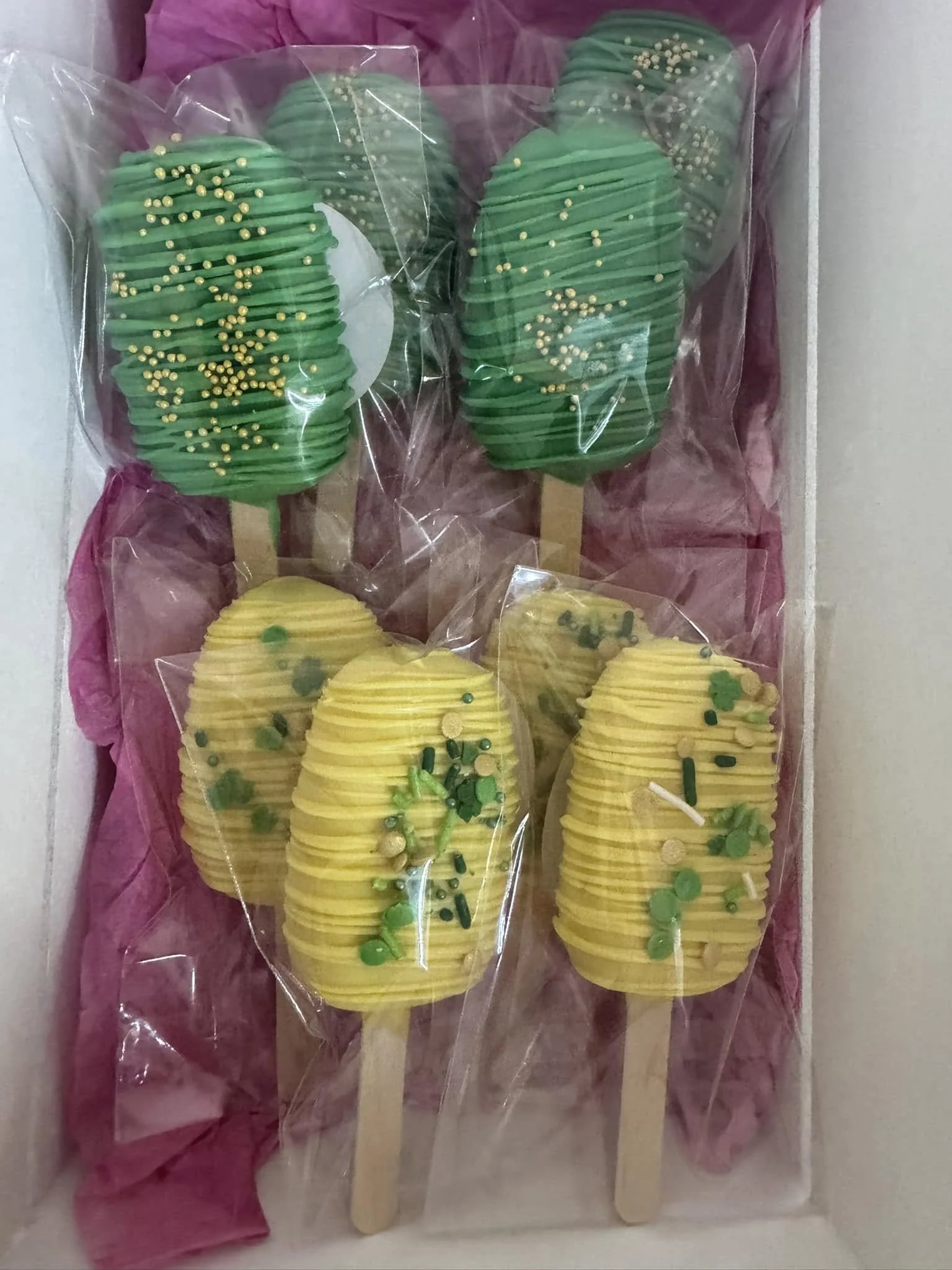 Cakesicles decorated  in green and yellow, with yellow and green sprinkles and gold beads