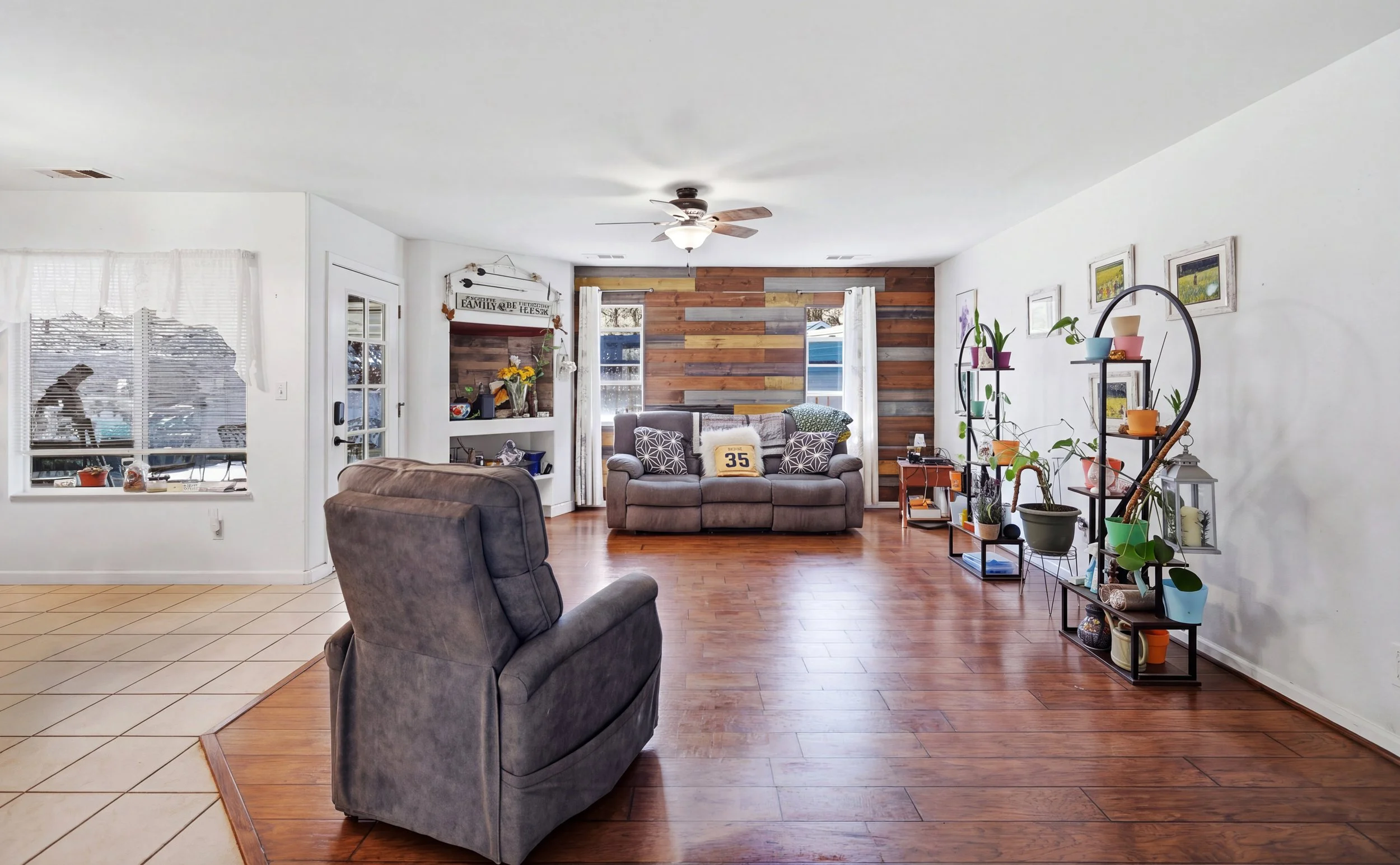 Living room with recliner, fireplace, wood flooring, and houseplants.