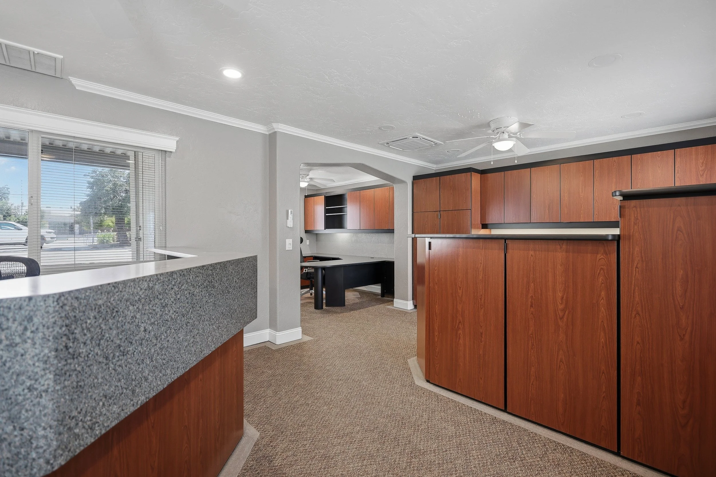 Kitchen with wood cabinetry, dark countertops, and recessed lighting.