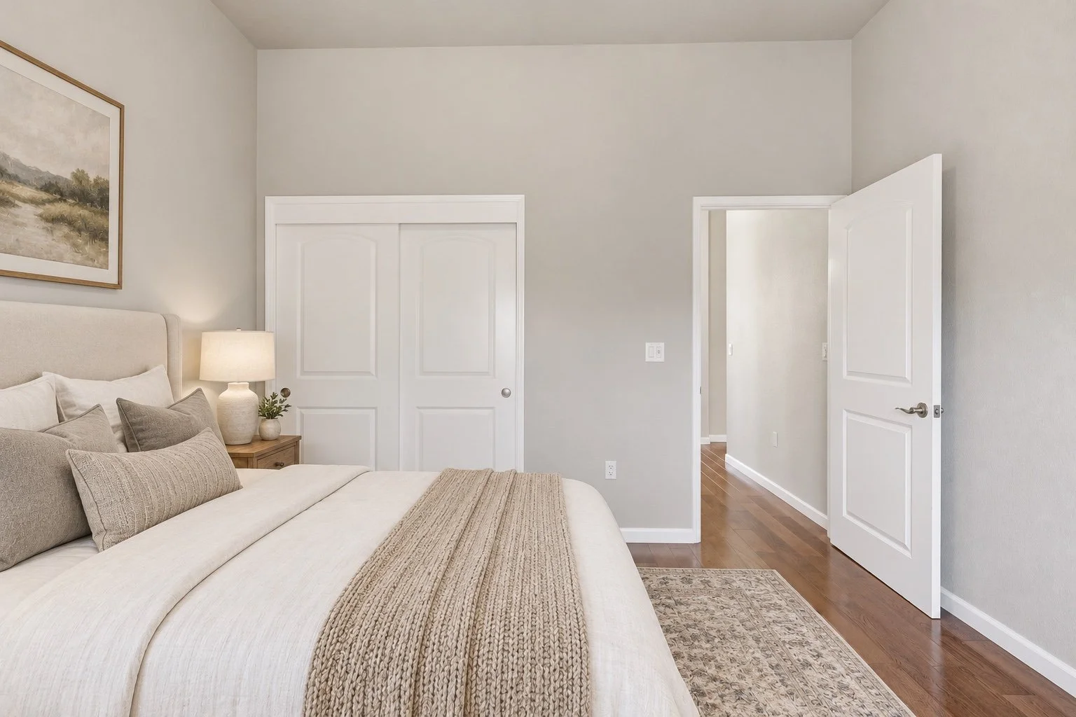 Virtually staged bedroom in an Oakdale home with neutral bedding and warm wood flooring.