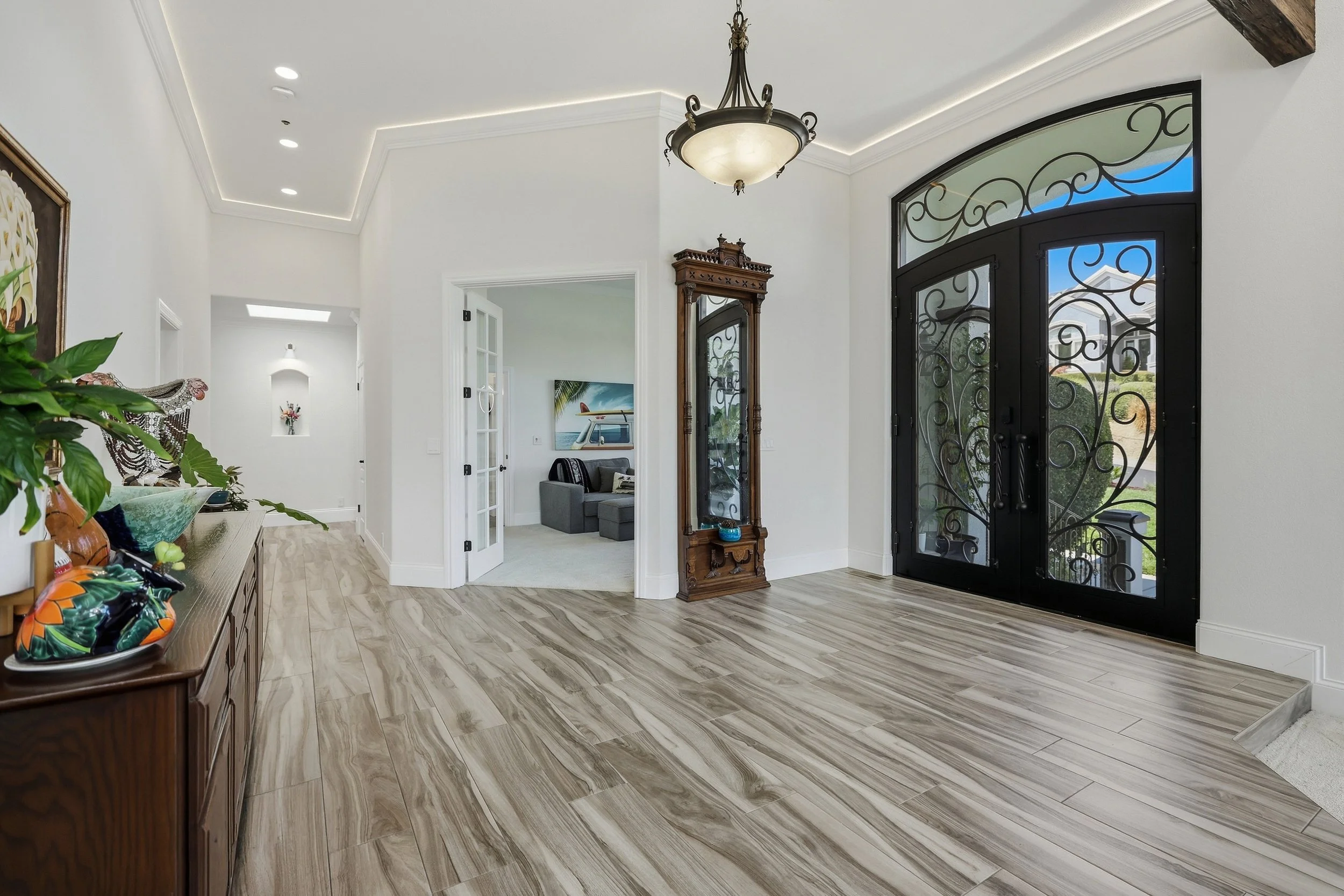 Entry hall with chandelier, wood flooring, and arched front doors.