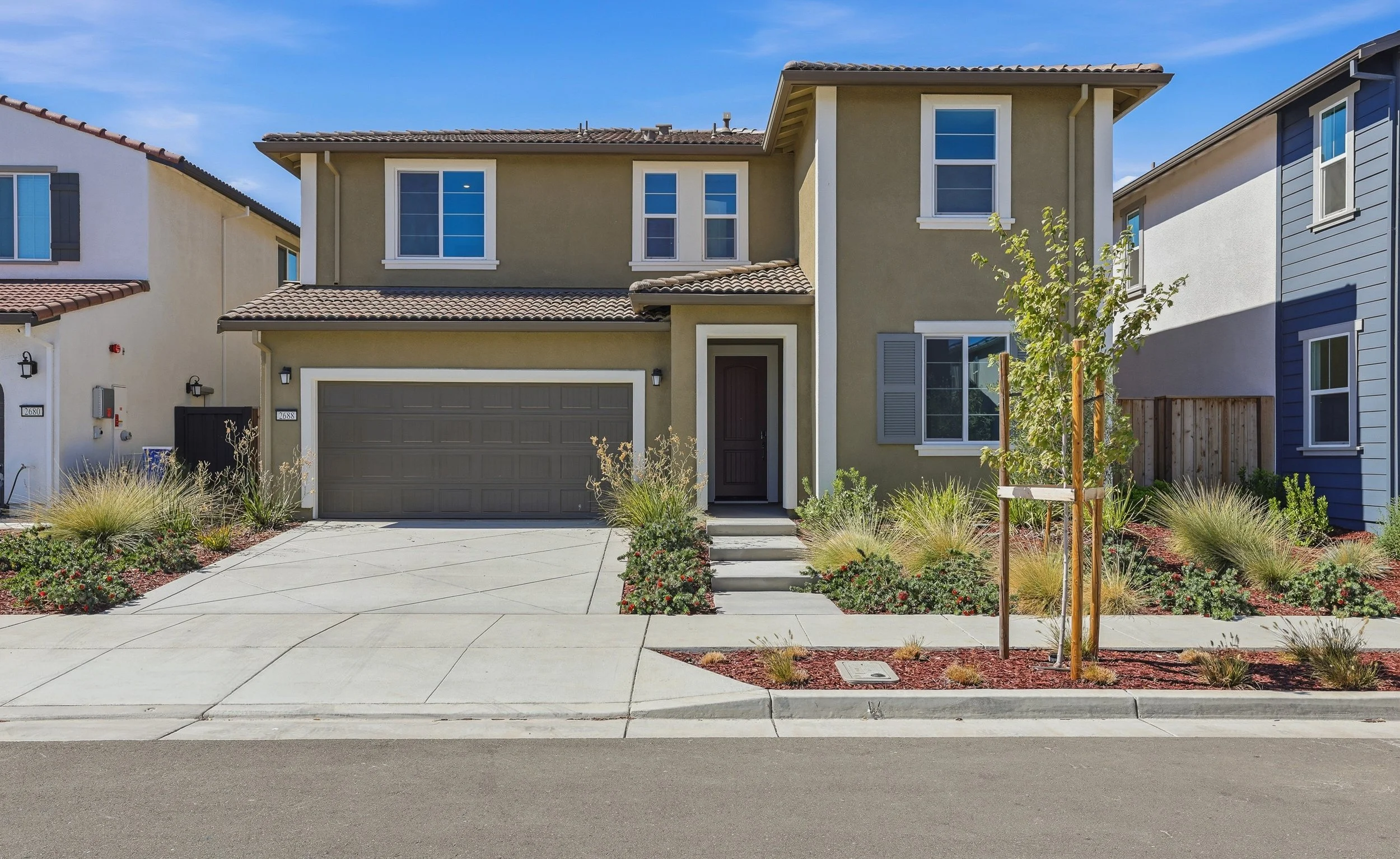 Two-story home with attached garage, driveway, and front garden.