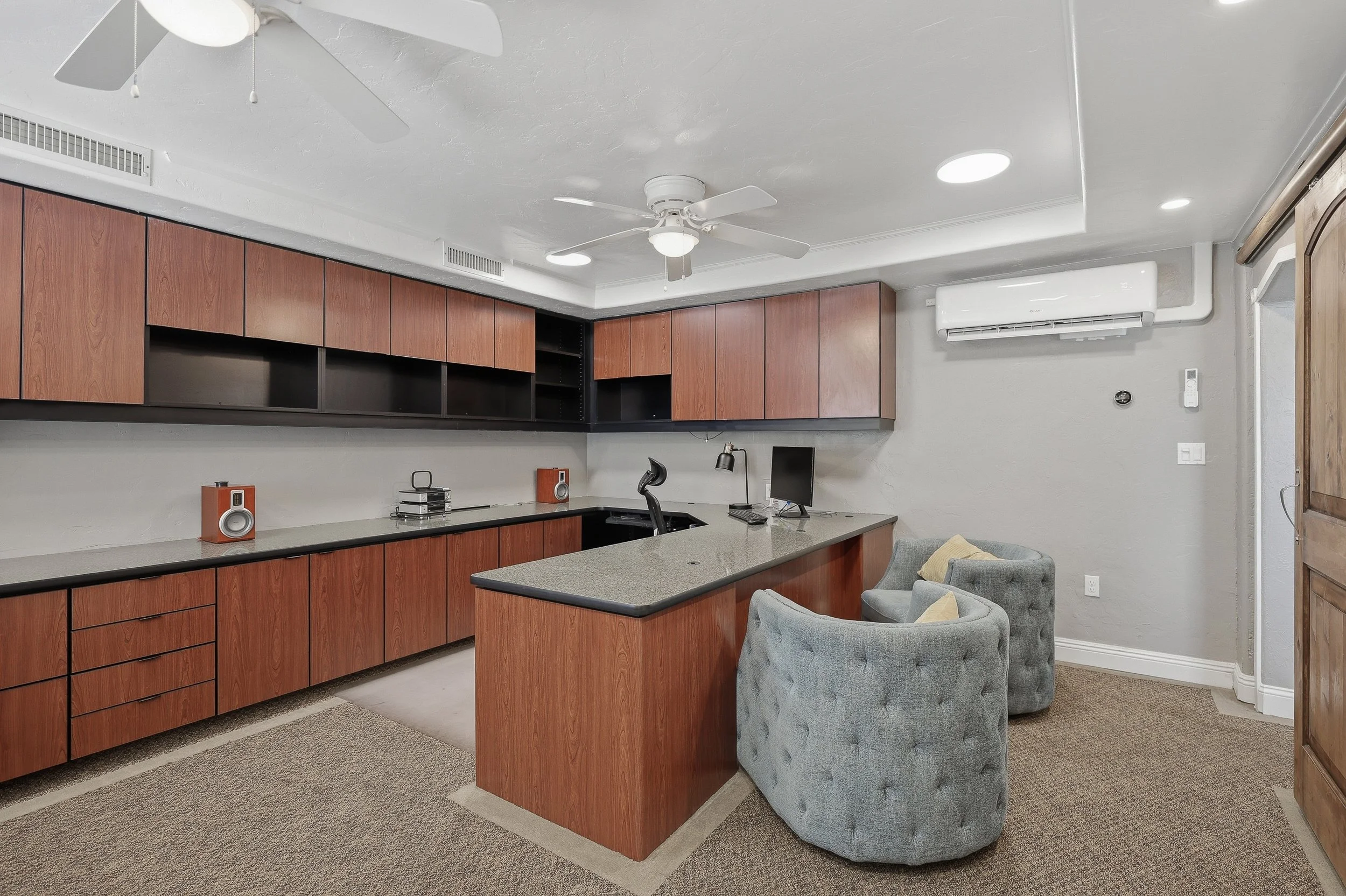 Kitchen with island, wood cabinets, stainless-steel range, and a patterned chair.