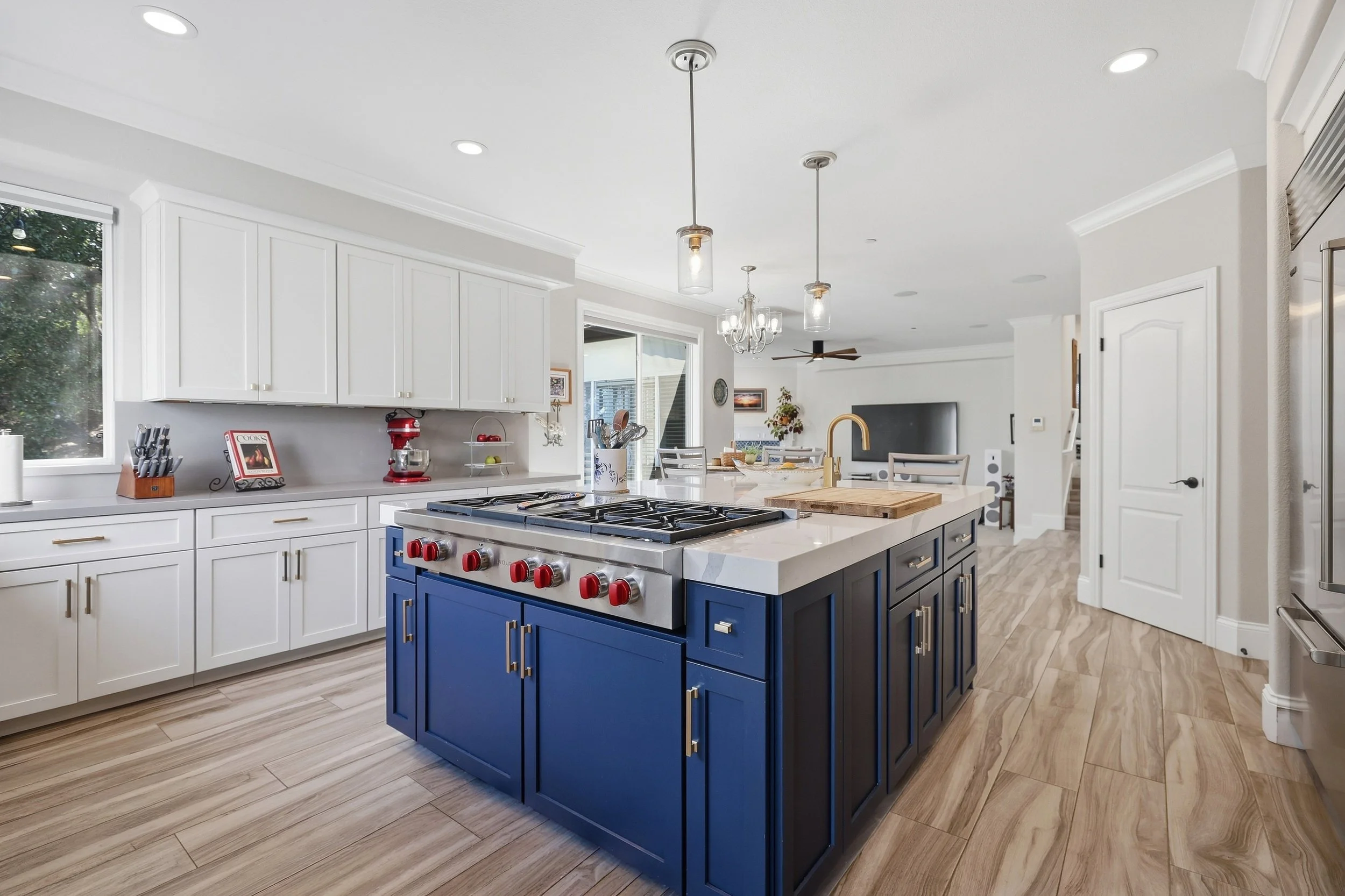 Bright kitchen with blue island cabinetry and pendant lights.