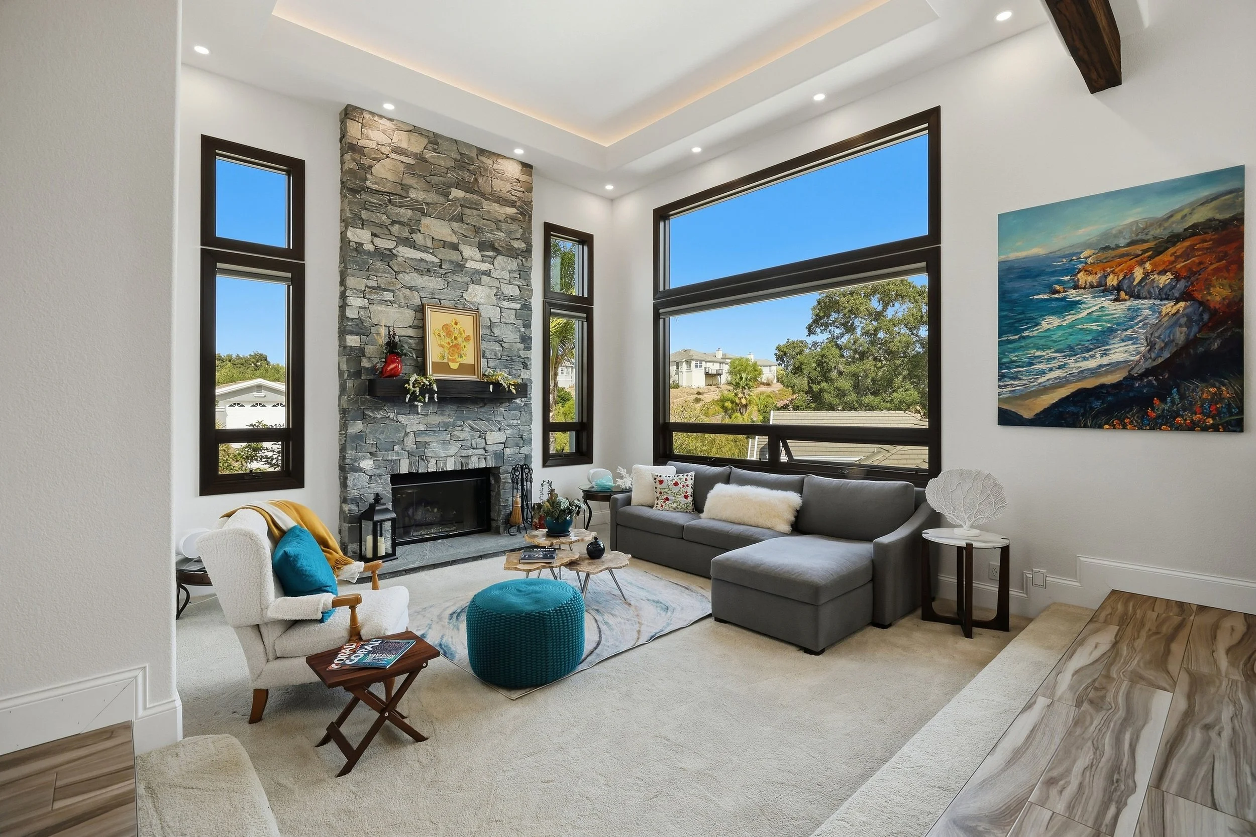 Living room with large windows, sofa, and a stone fireplace.