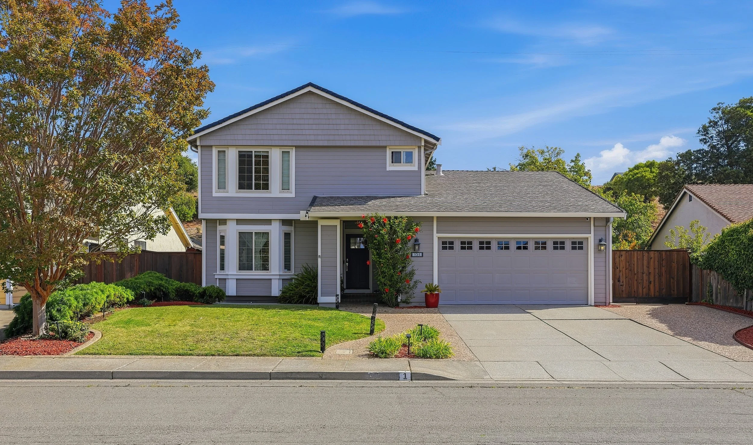 Two-story gray home in Hercules with garage, lawn, and landscaped entrance.
