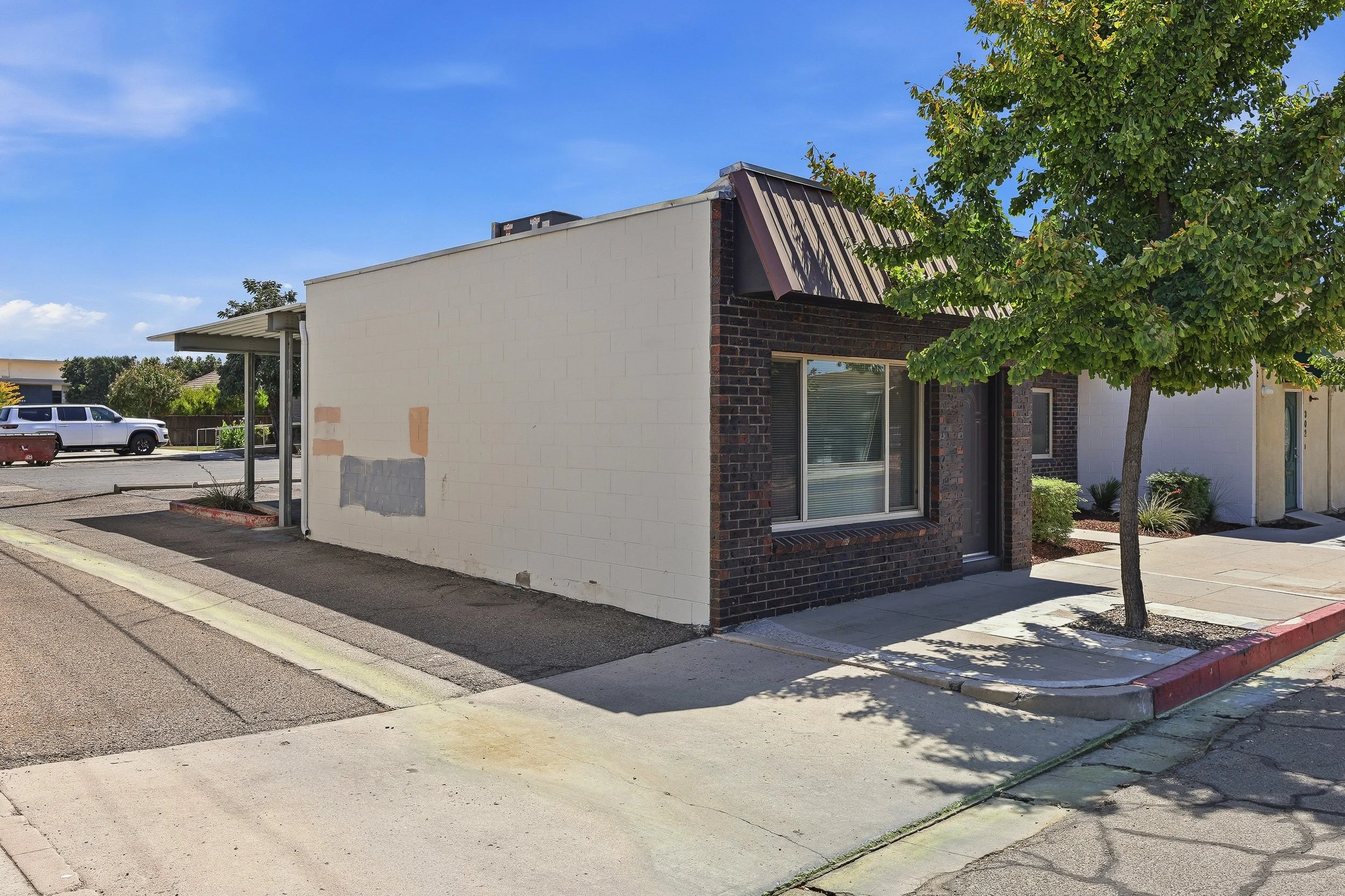 Side exterior of a commercial building with large windows and paved access.