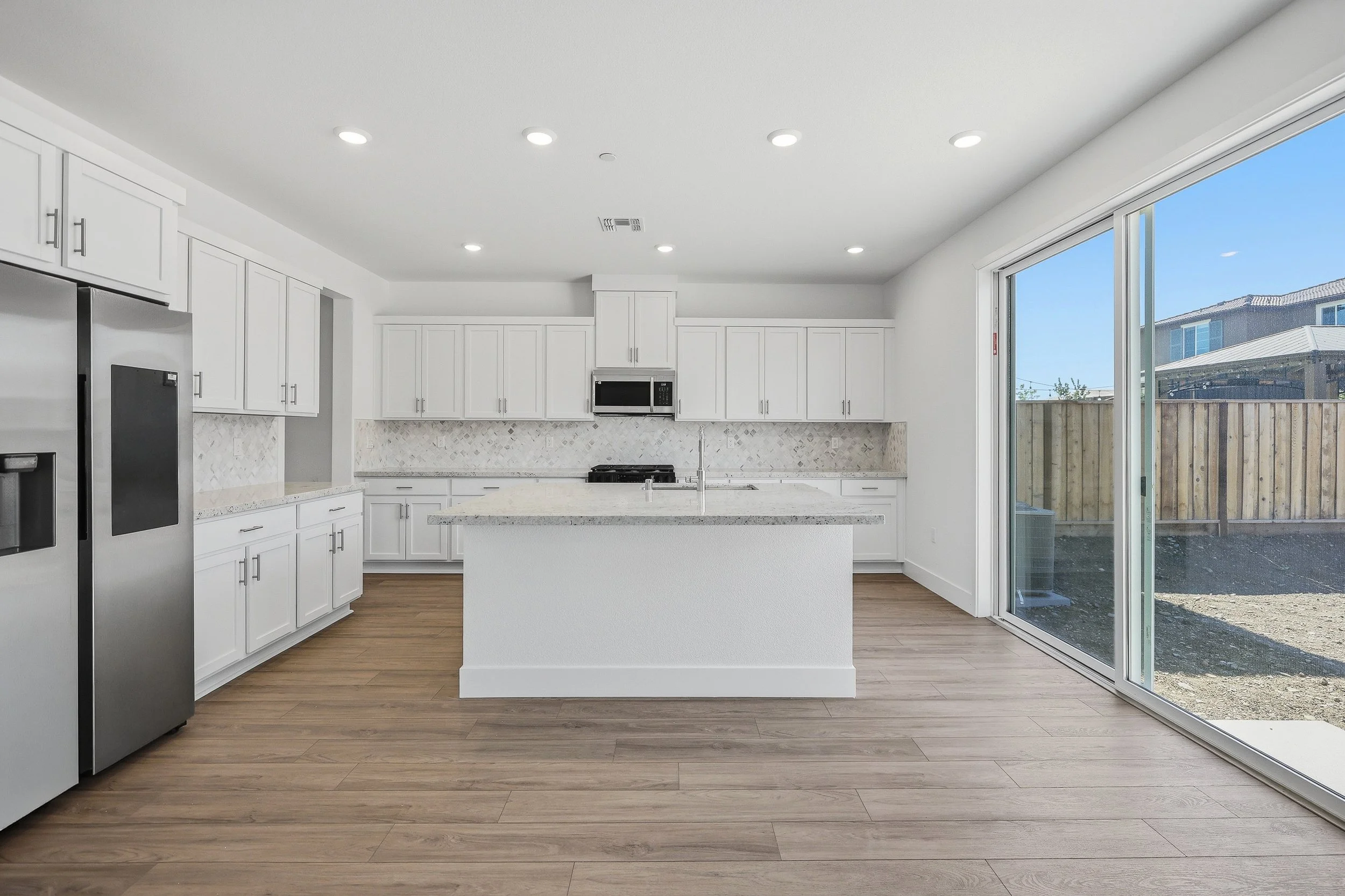 Bright white kitchen with large island and wood flooring.